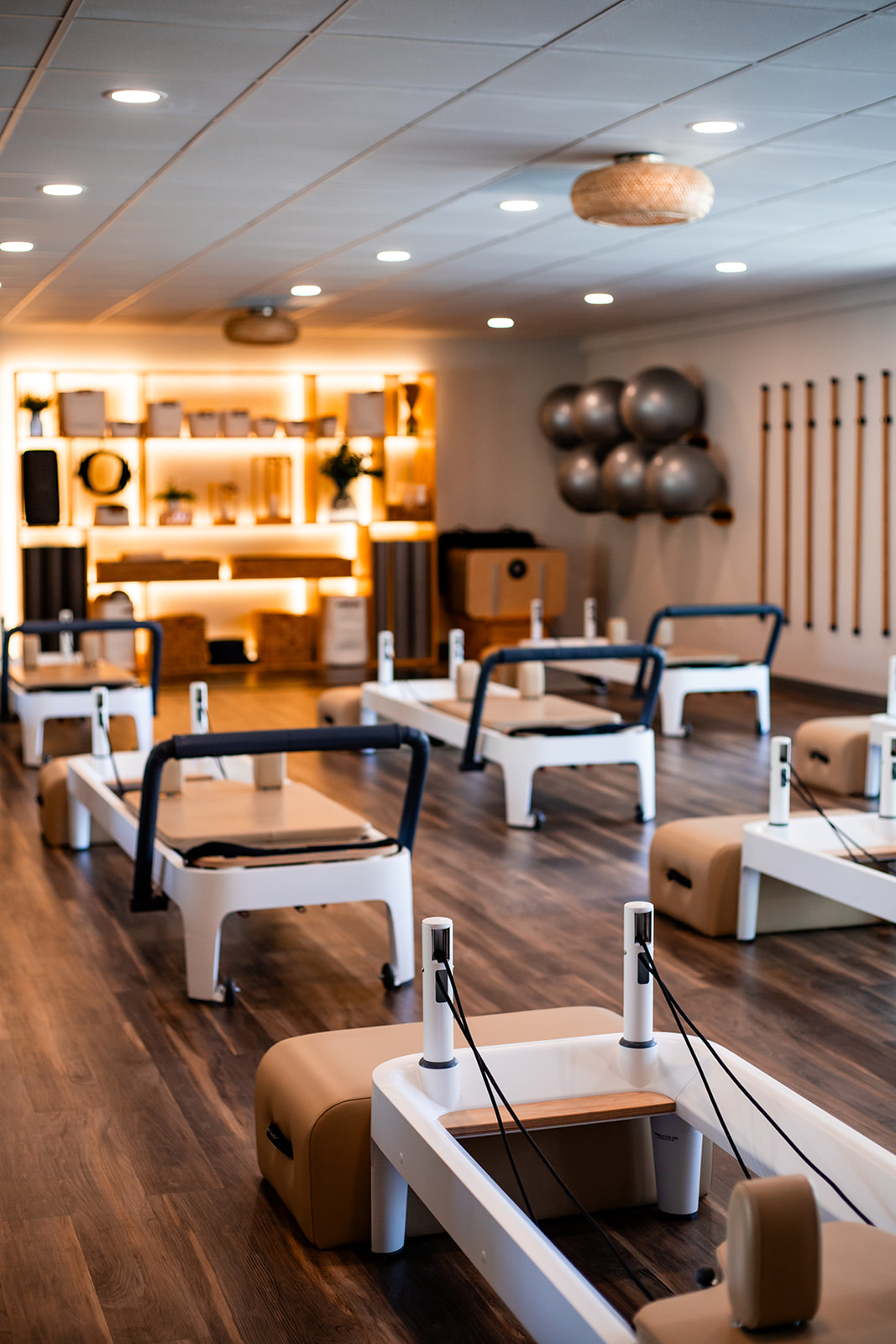 Rehabilitation or physical therapy room with beds, equipment, and a wooden floor, illuminated by ceiling lights.