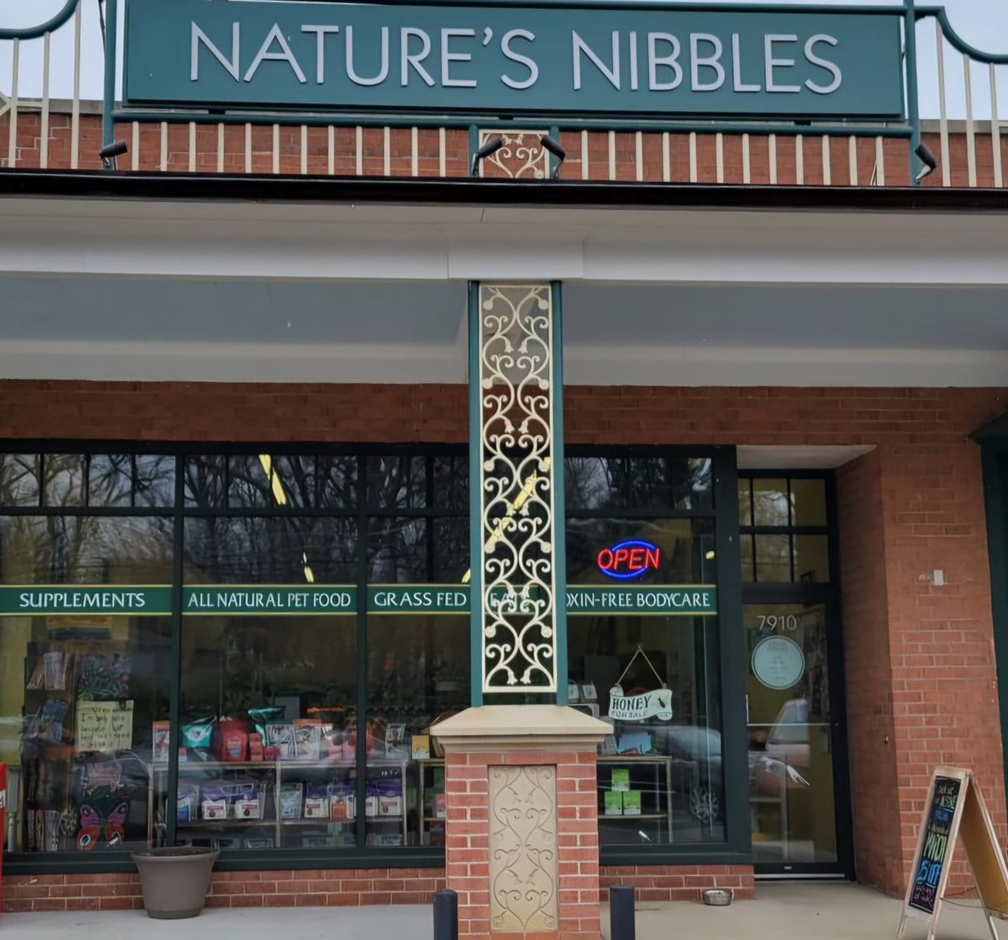 Store named 'Nature's Nibbles' with a sign, glass door, and window displaying products, and an 'Open' sign visible.