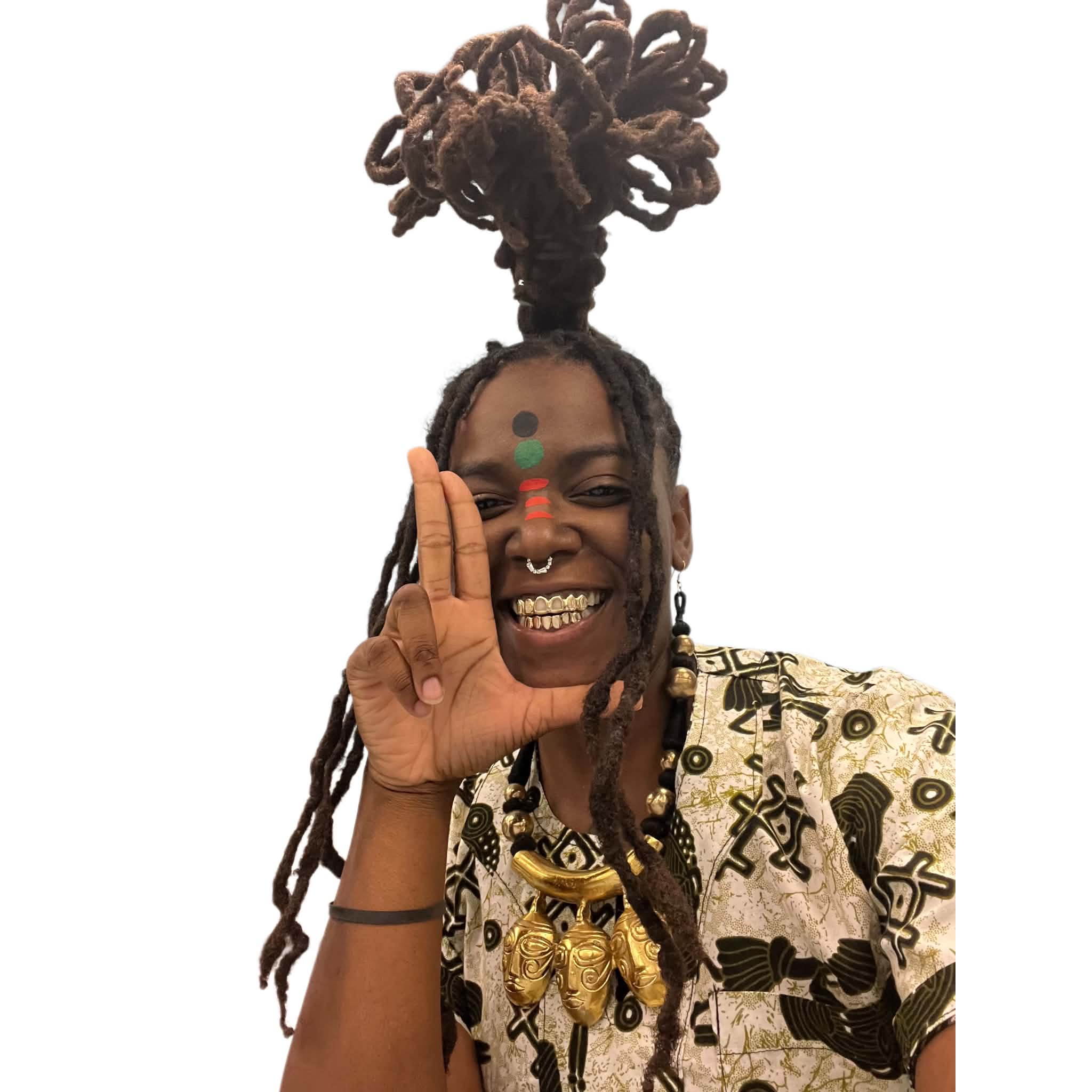 Person with dreadlocks styled in a high bun, smiling, holding up a hand with fingers forming an L shape, wearing patterned clothing and jewelry.