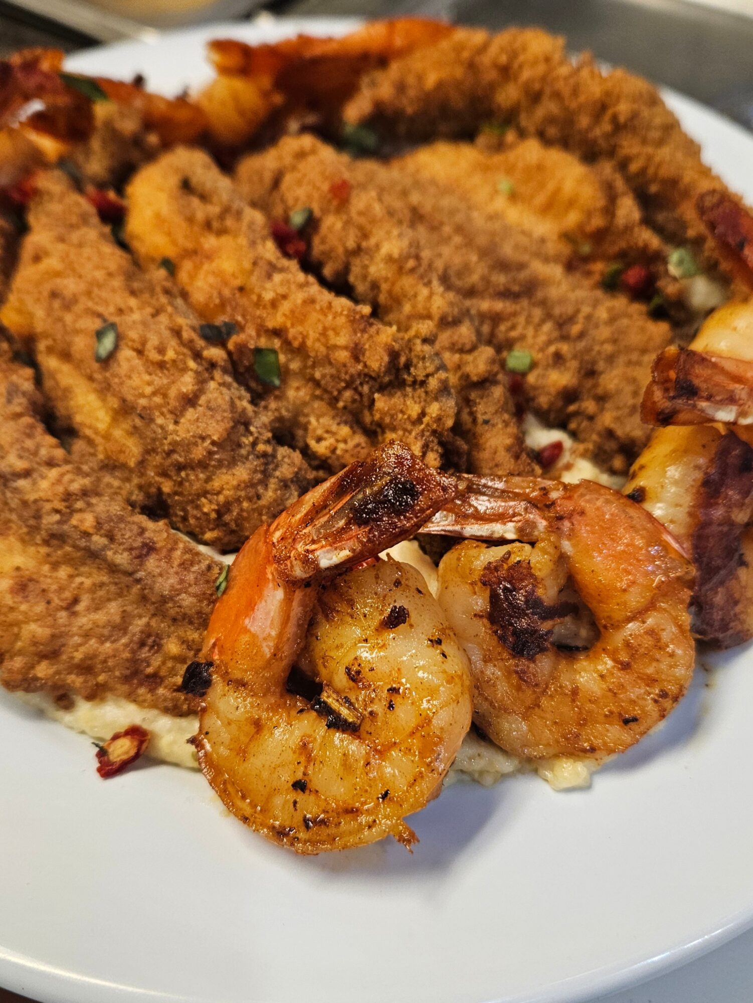 Fried shrimp and breaded fish fillets on a white plate, garnished with herbs.
