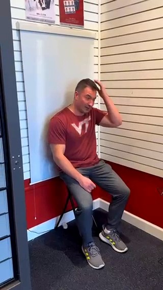 Man sitting on a chair, touching his head, in a room with striped walls.