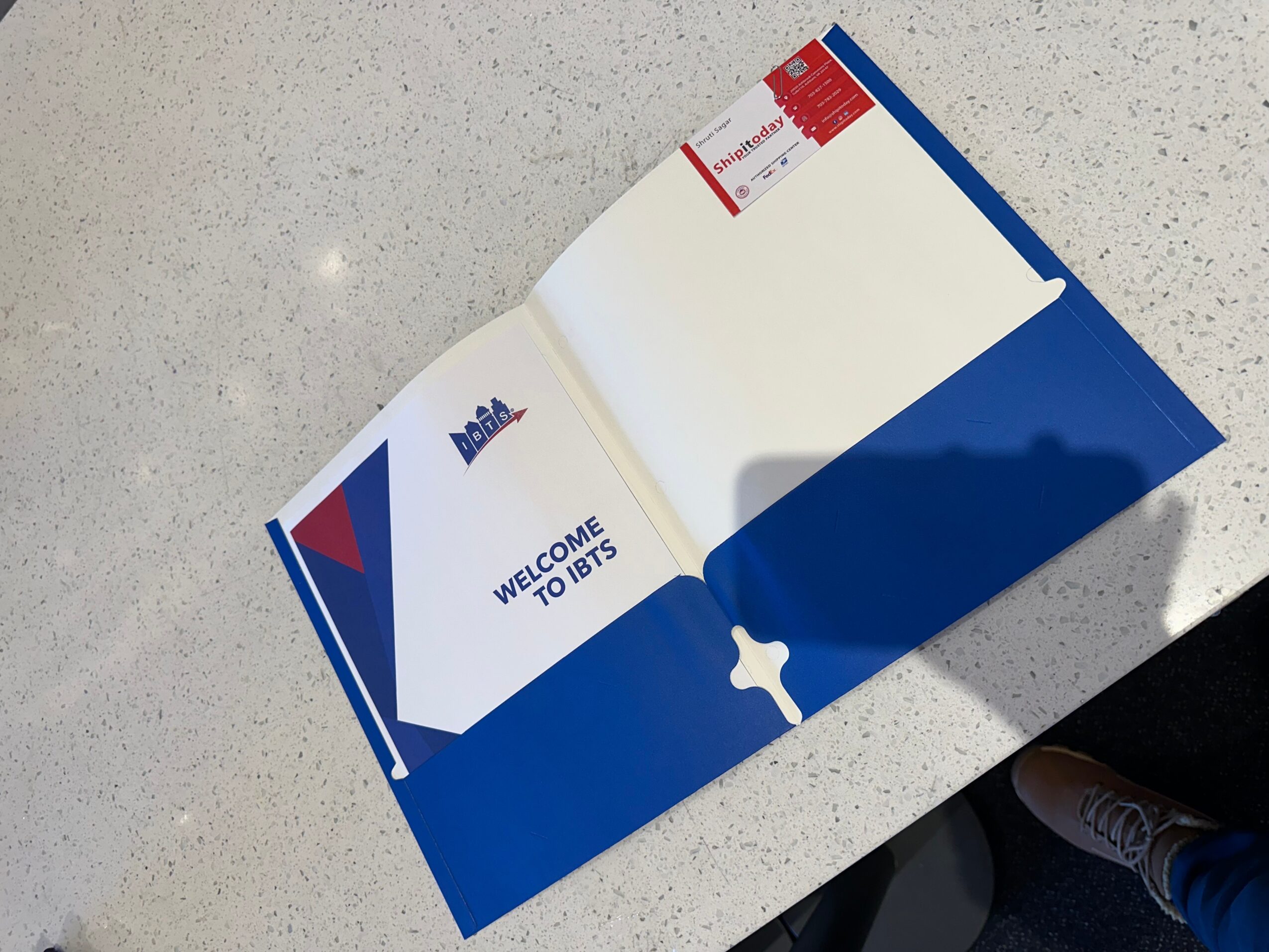 Open booklet on a white surface, showing a welcome message and a red and white ticket inside.