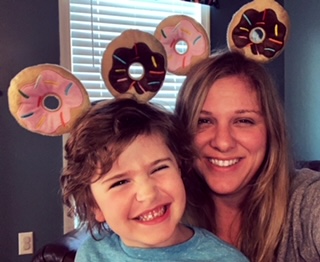 A woman and a child smiling with donut-shaped pillows in the background.