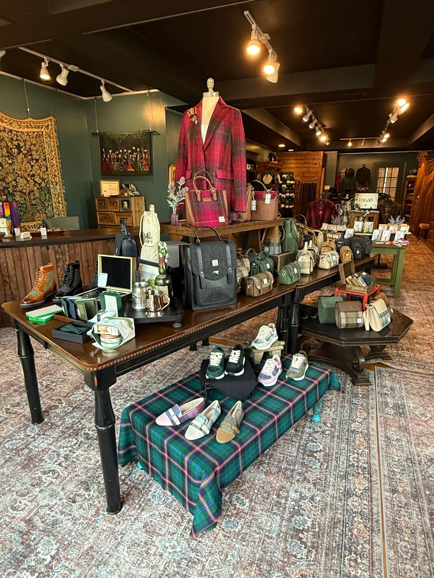 Room with a table filled with bottles, glasses, and a backpack, a plaid sofa, and a patterned rug.