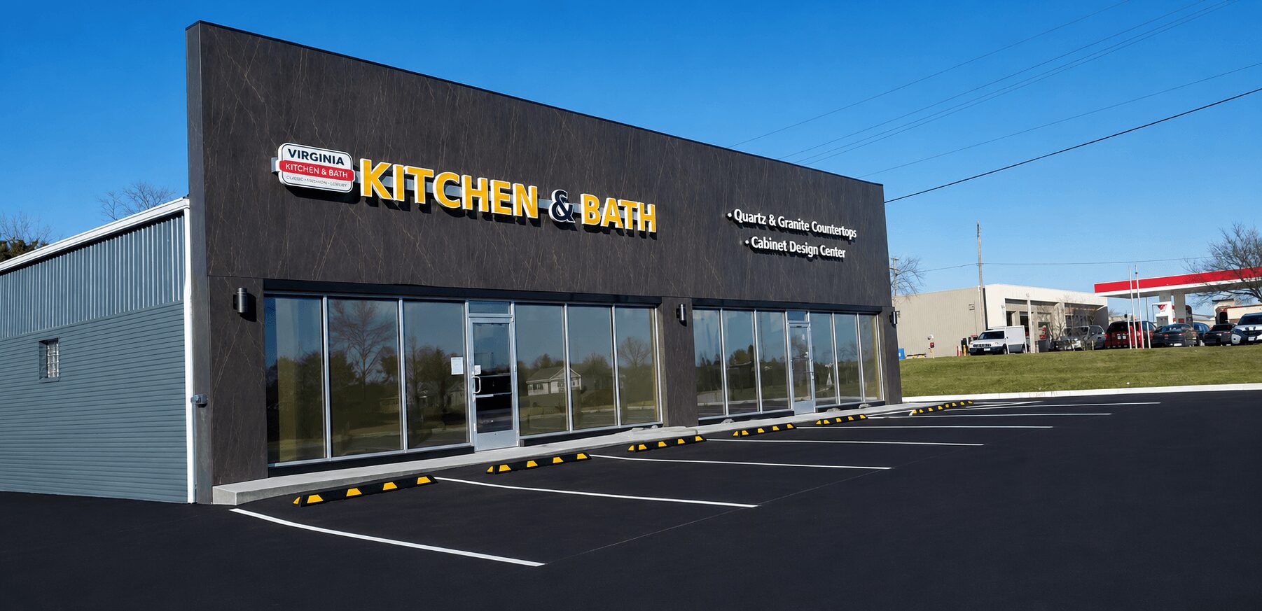 Commercial building with large glass windows and a sign that reads 'KITCHEN & BATH' against a blue sky.