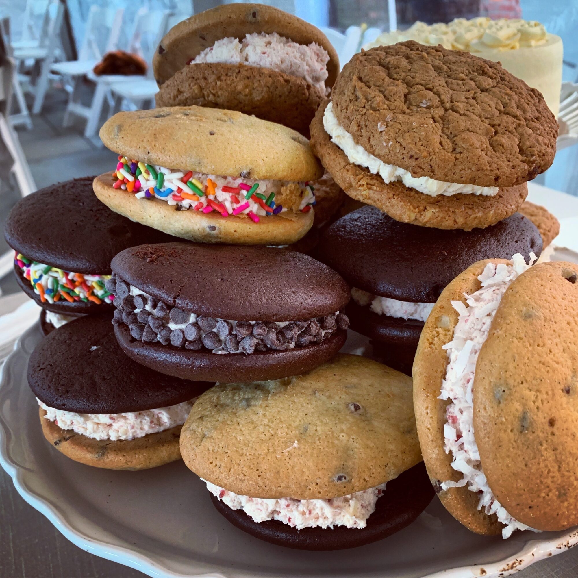 Assorted cookies and ice cream sandwiches on a plate, with a blurred background of a cafe setting.