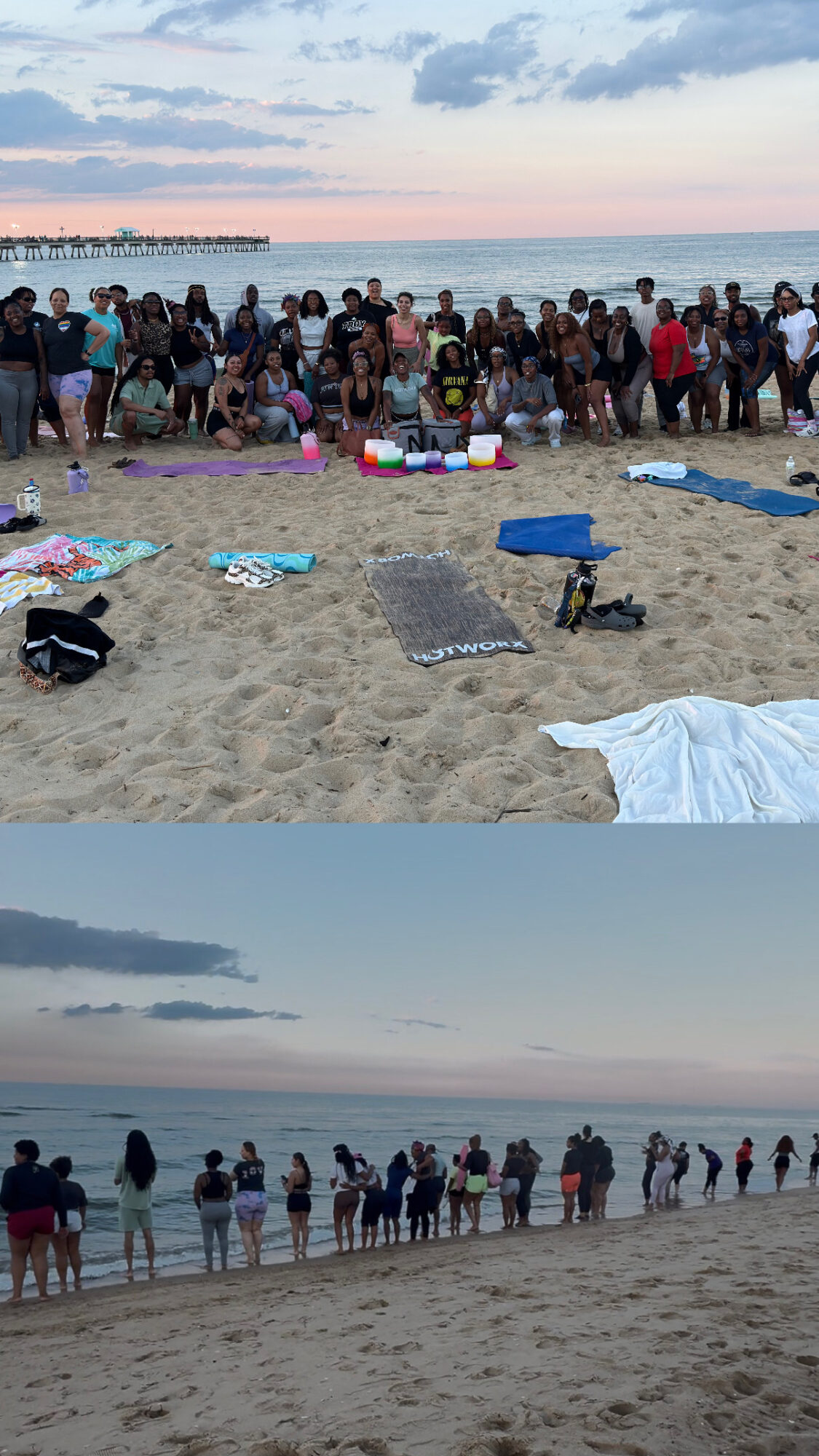 Large group of people gathered on a beach near the water, with towels and belongings on the sand, cloudy sky above.