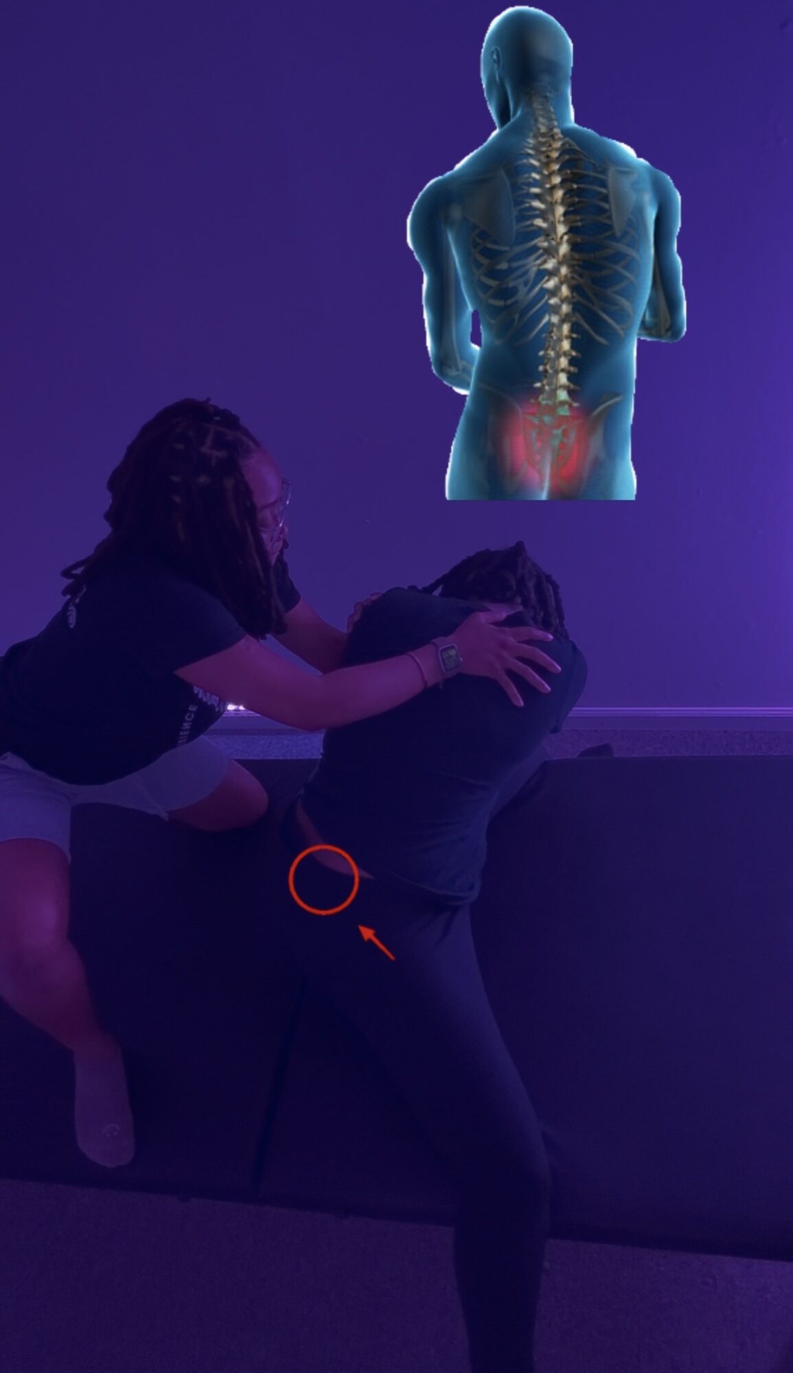 Person sitting on a couch with a woman leaning over, pointing at their back, with a medical diagram of the human spine above.