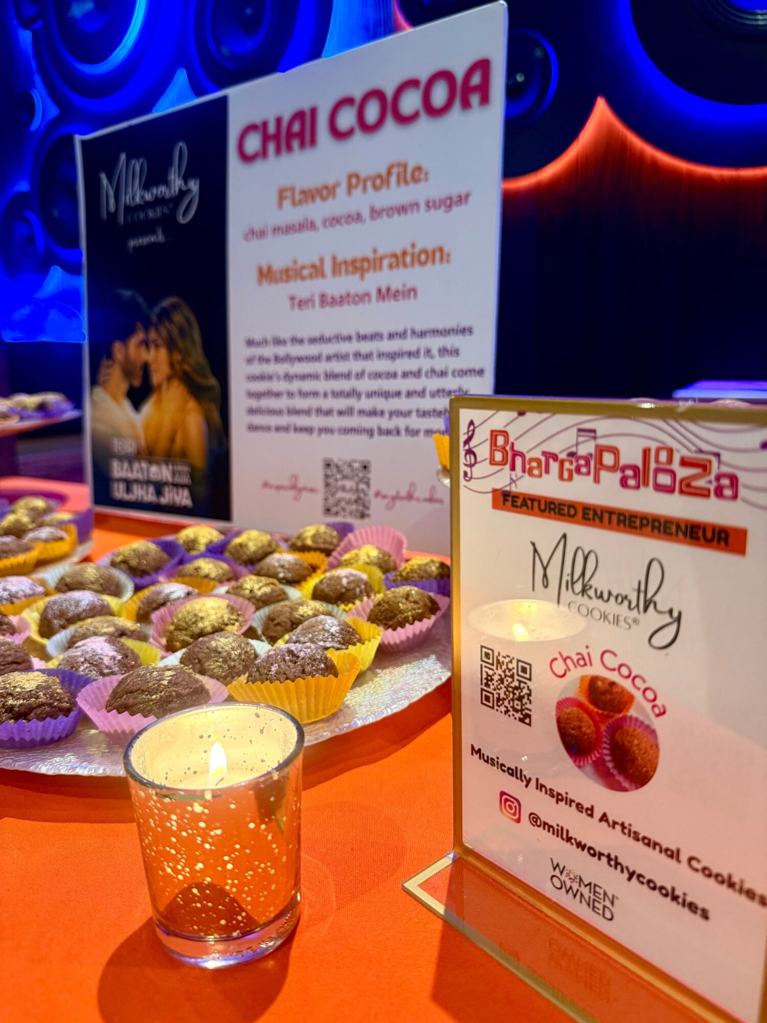 Display of assorted chocolates, a lit candle, and signs promoting Chai Cocoa and Bhangra Palooza event.