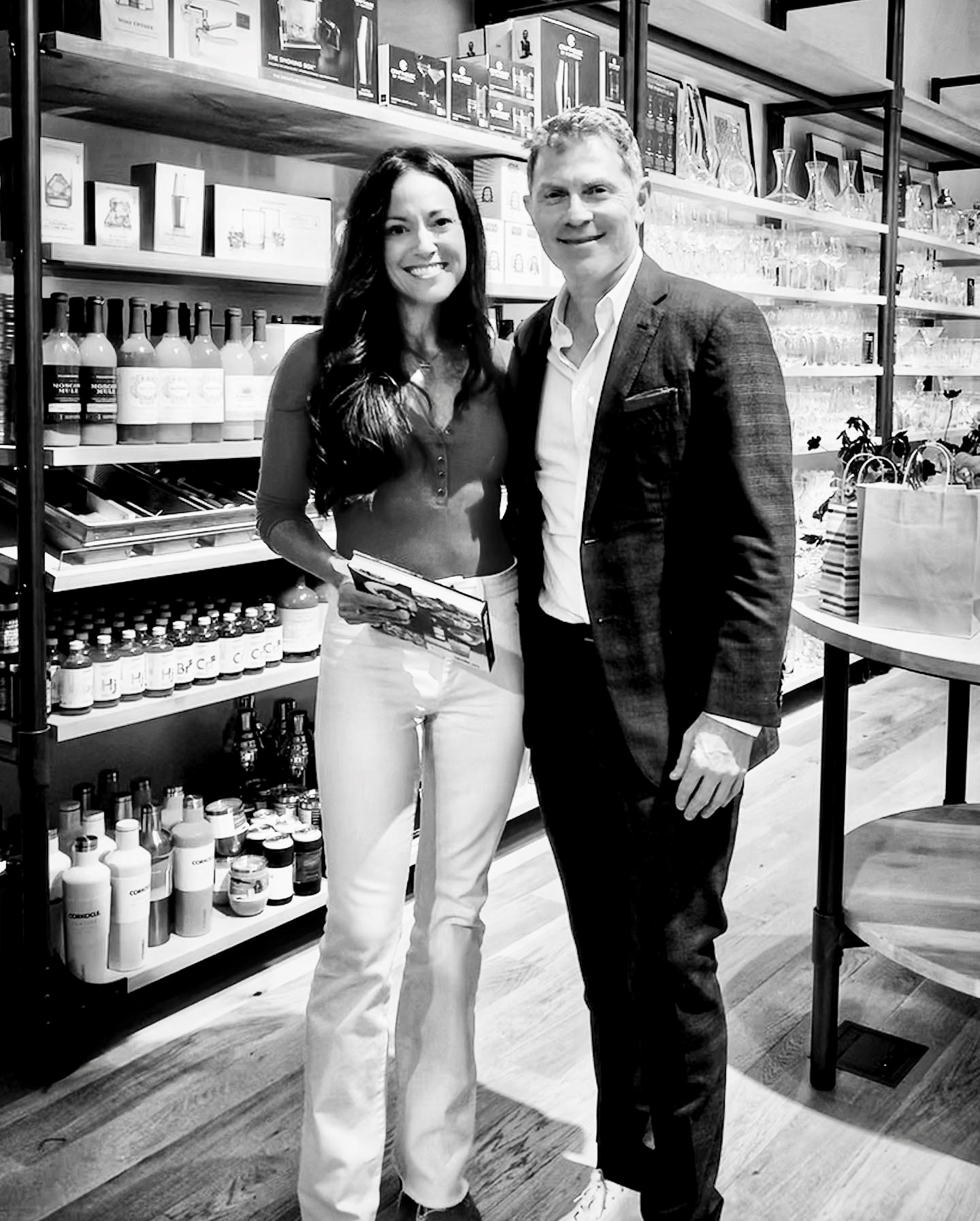 Two people, a woman and a man, standing together in a store aisle with shelves of products behind them.