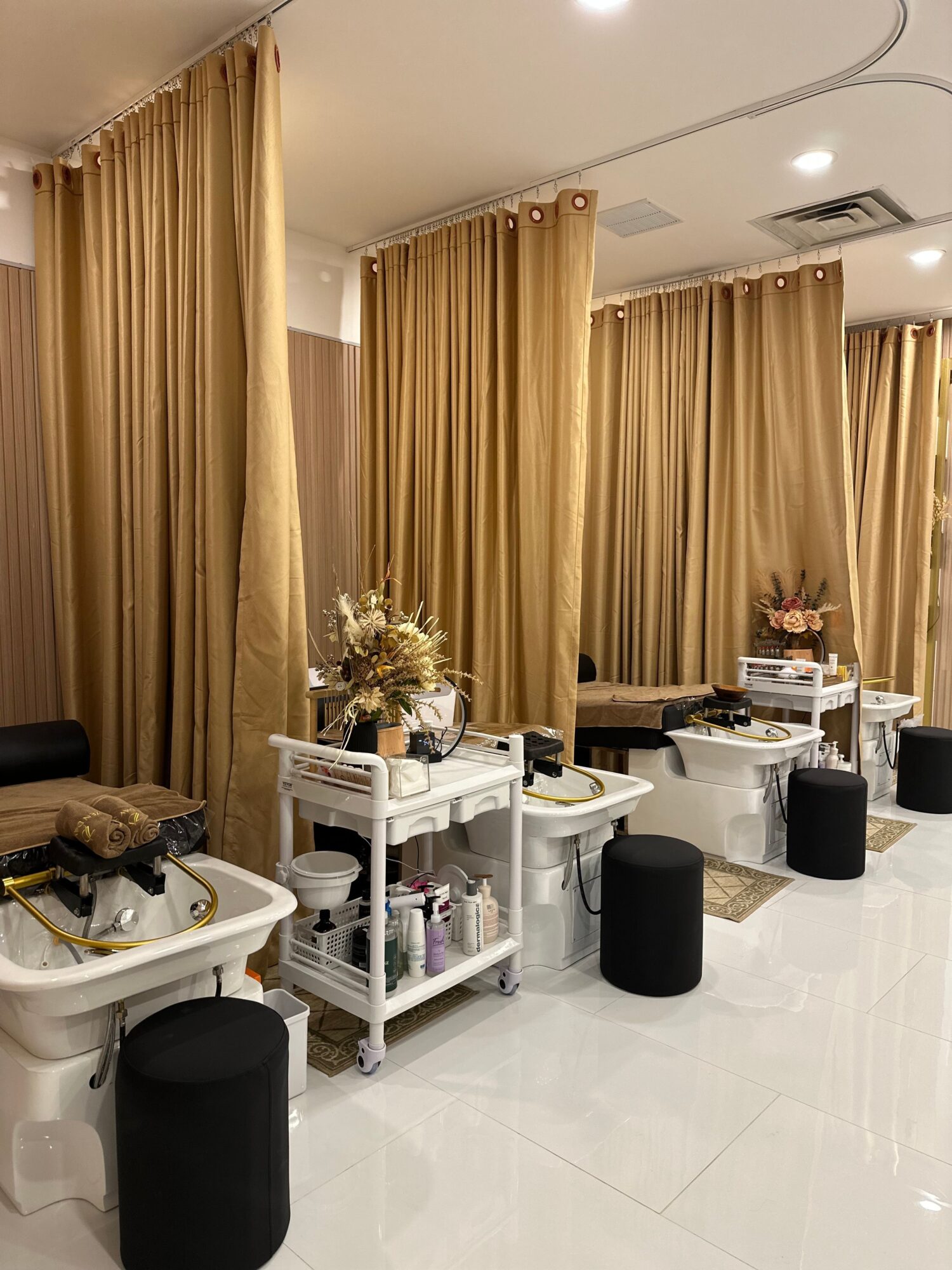 Dining area with tables, black chairs, and beige curtains, decorated with flowers and tableware.