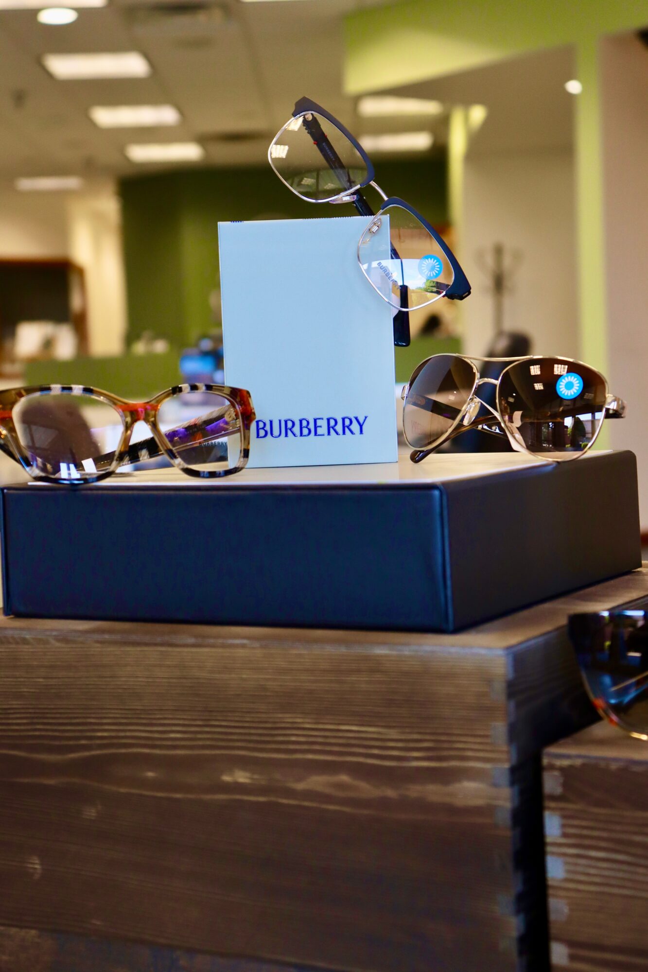 Display of sunglasses on a table with a Burberry box in the background, in a store setting.