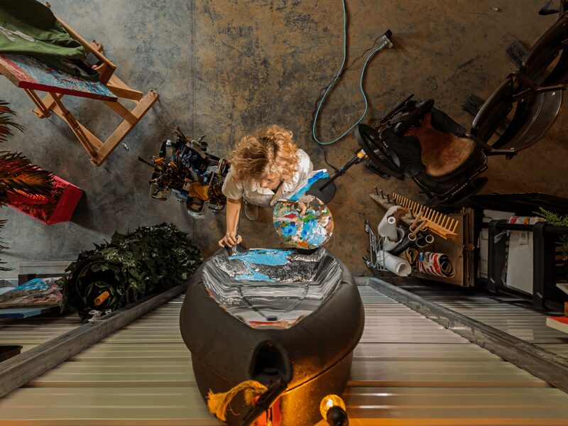 Upside-down view of a cluttered garage with a person, bicycle, and various objects, including a table and a red bag.