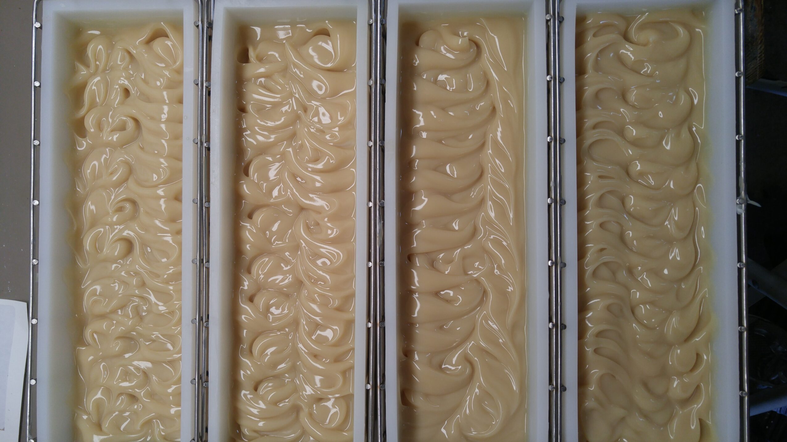 Four containers filled with light-colored, swirled ice cream or frozen dessert, viewed from above.