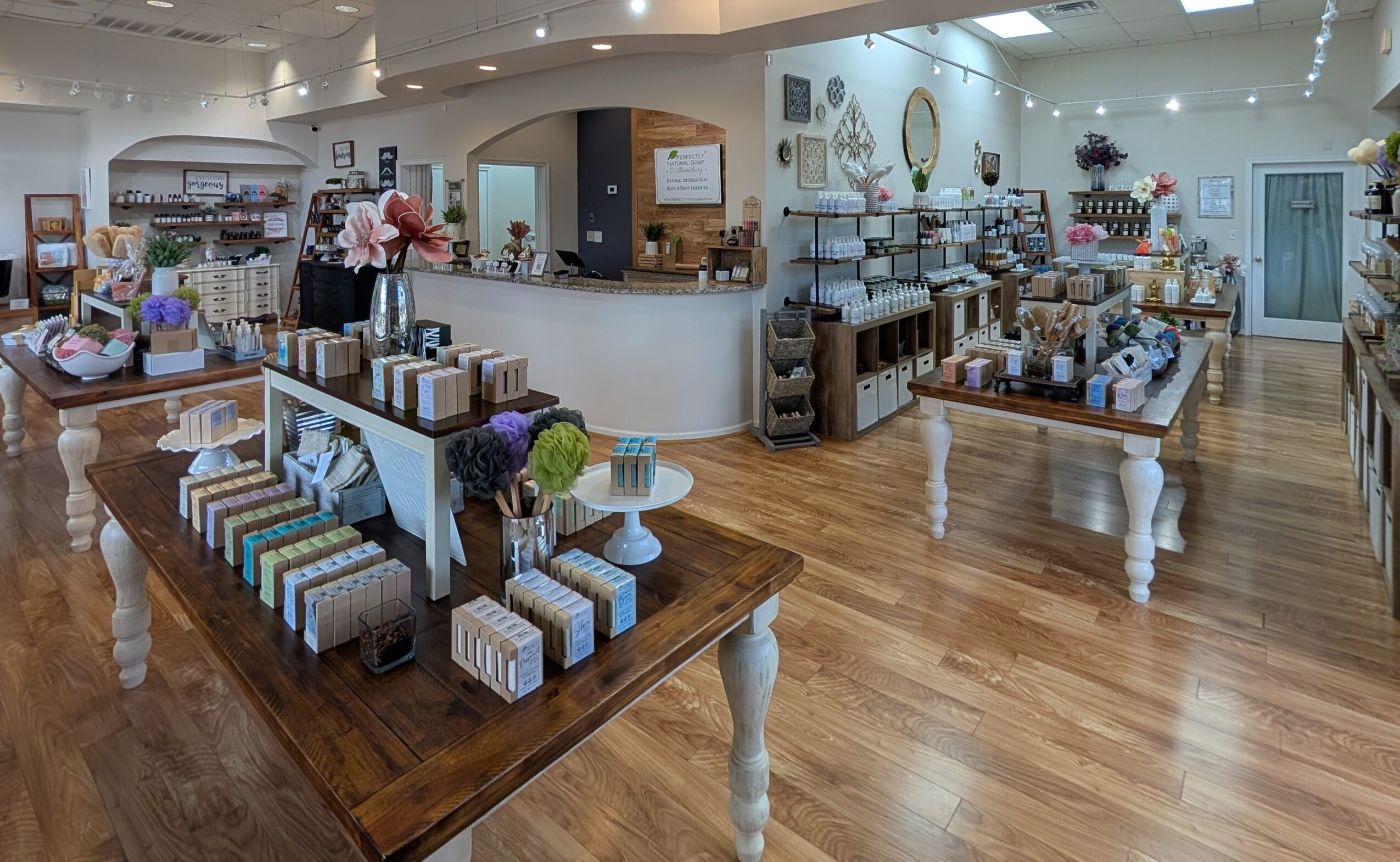 Interior of a store with tables displaying gift boxes, shelves with home decor, and a wooden floor.
