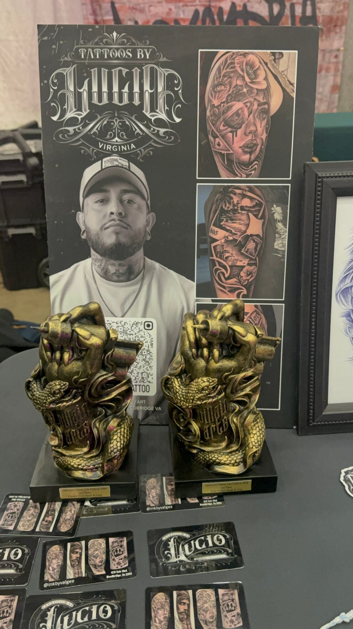 Poster featuring a man with tattoos and two detailed tattoo designs, with two gold-colored lion statues in front.
