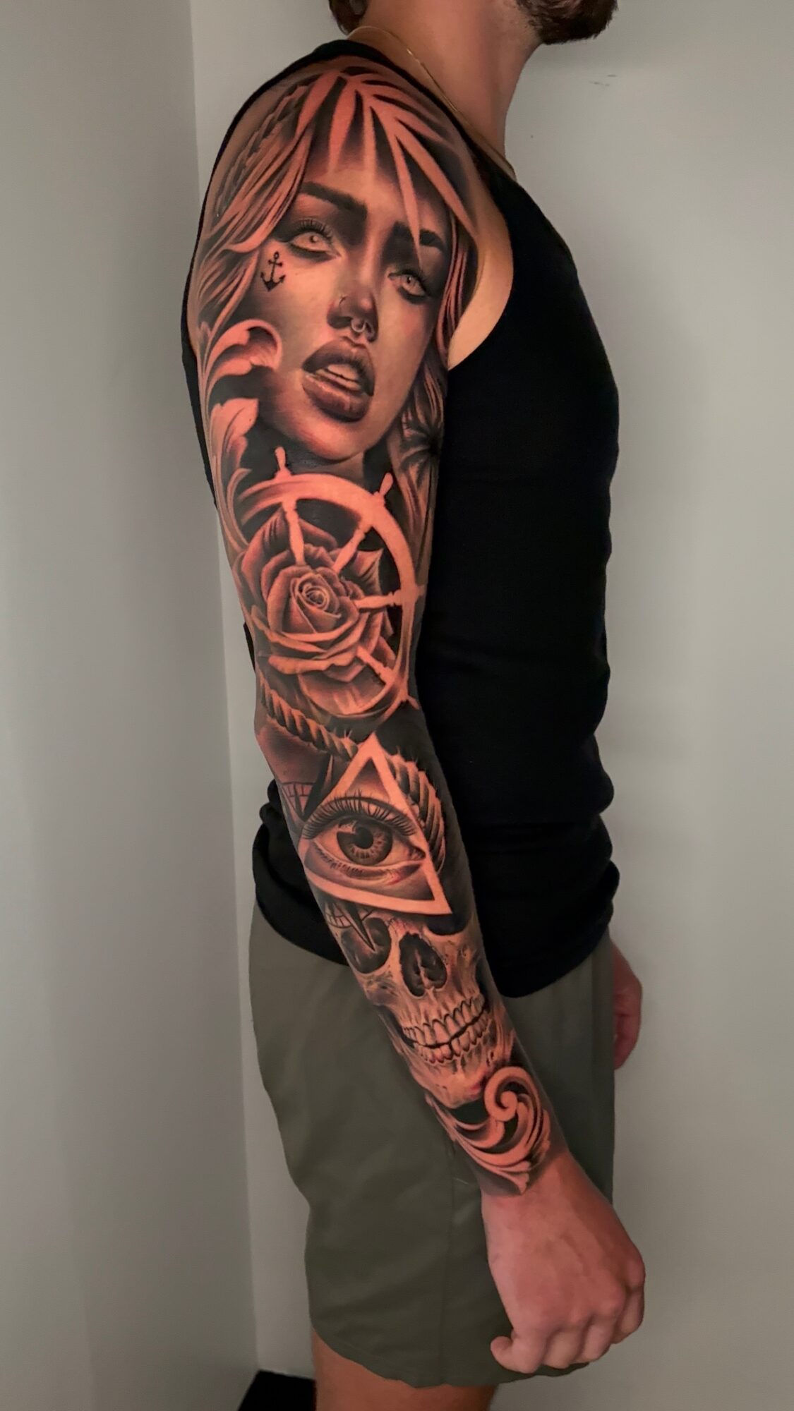 Tattoo sleeve featuring a woman's face, geometric patterns, an eye, and abstract designs on a person's arm.