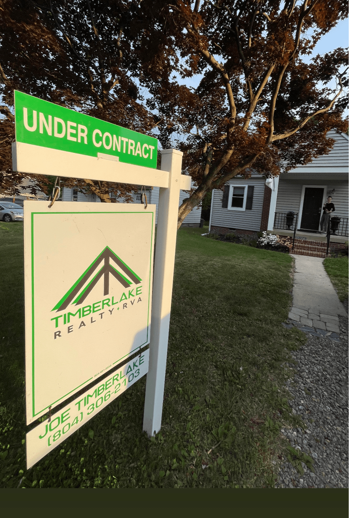 Real estate sign with Timberlake Realty logo and contact information, under a tree in front of a house, with an 'Under Contract' banner.