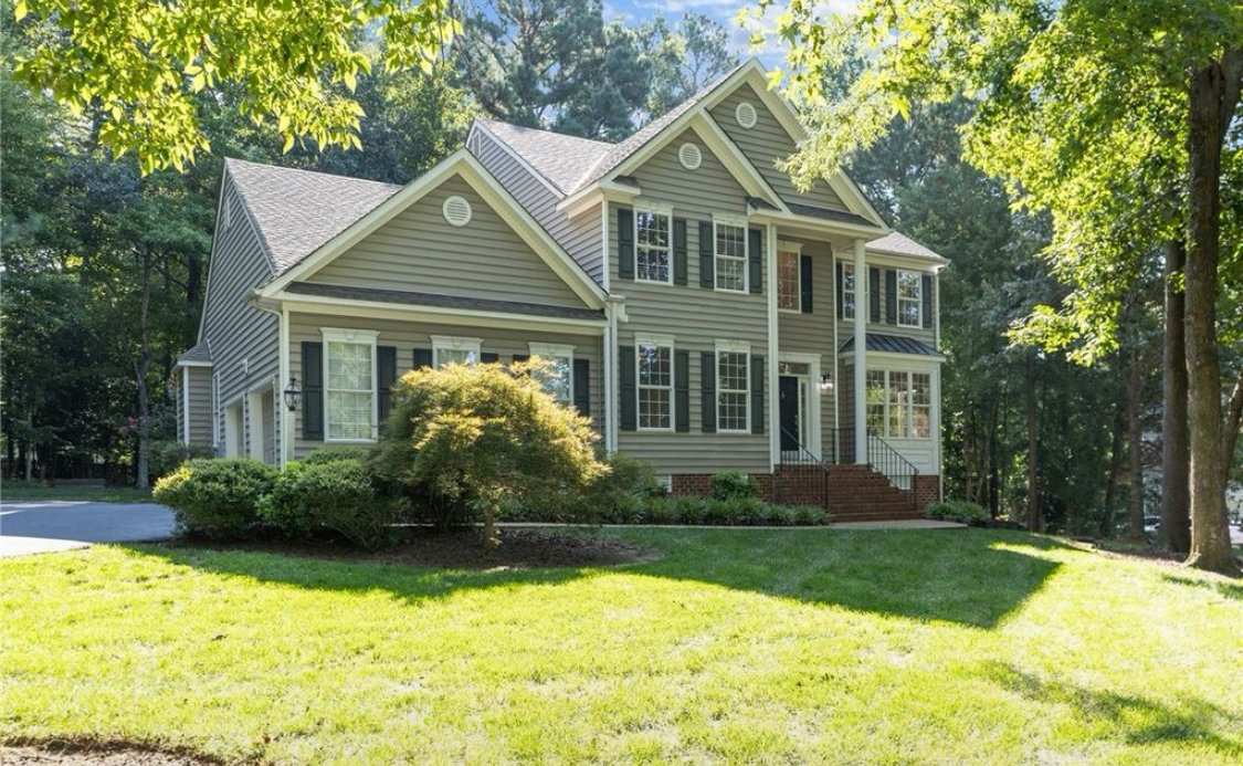 Large house with multiple gabled roofs, surrounded by trees and a well-maintained lawn.