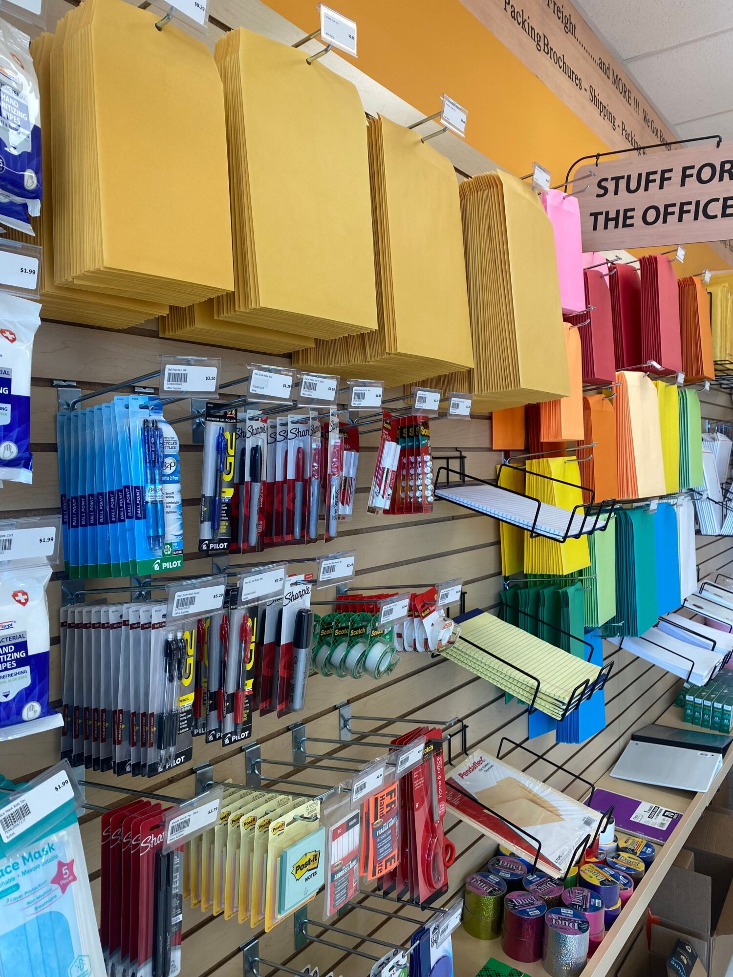 View of office supplies including yellow envelopes, pens, notebooks, and binders on a desk.