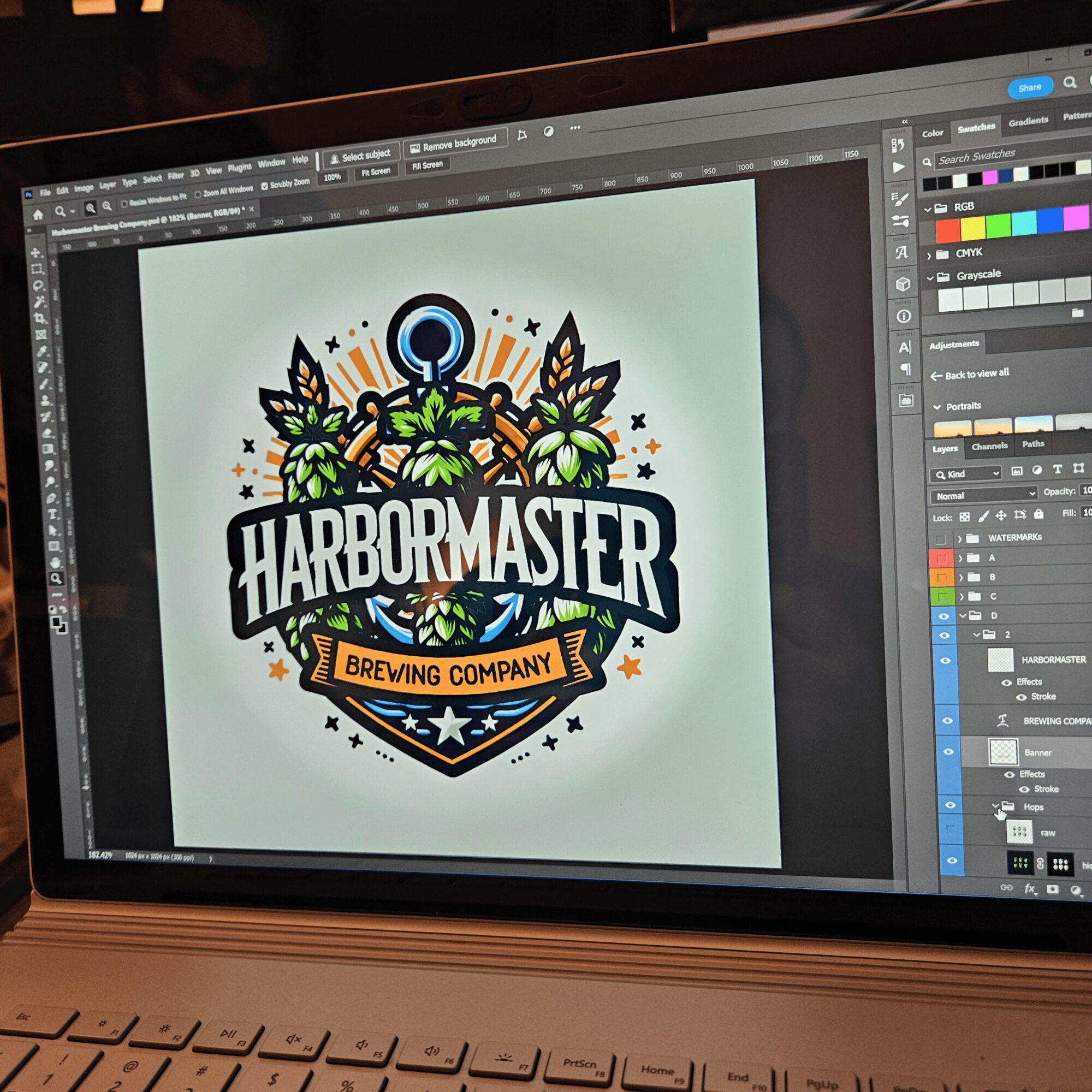 Computer screen displaying a colorful logo for HarborMaster Brewing Company with hops, leaves, and a ship's wheel.