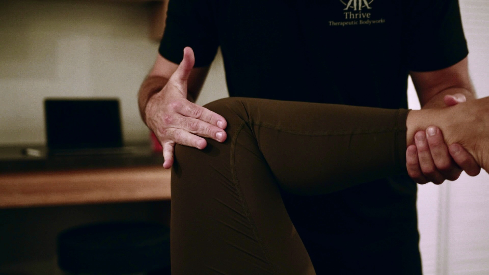 Person holding another person's knee during a physical therapy session, focusing on the knee and hand positions.