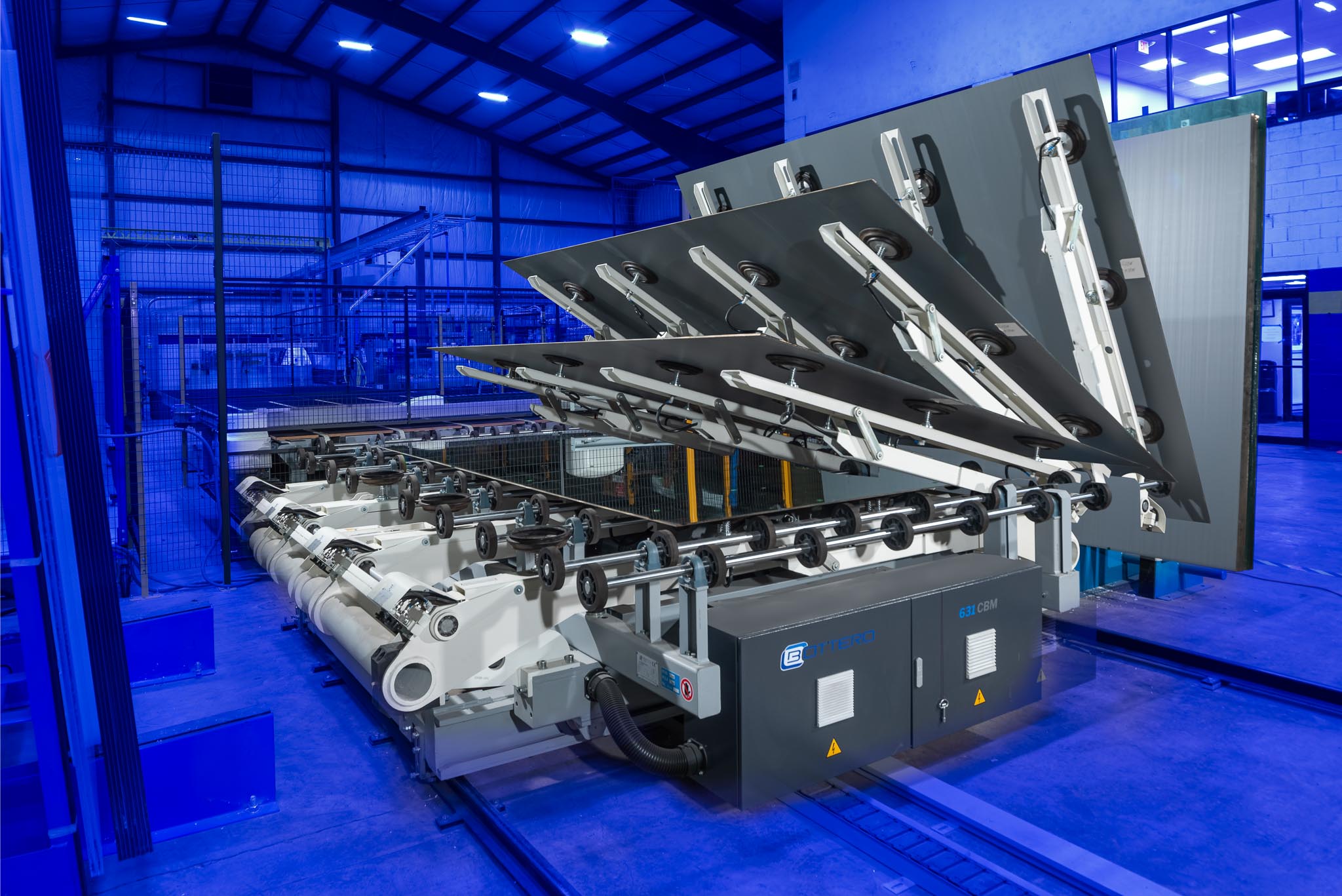 Large industrial printing machine inside a spacious, well-lit facility with blue lighting and high ceilings.