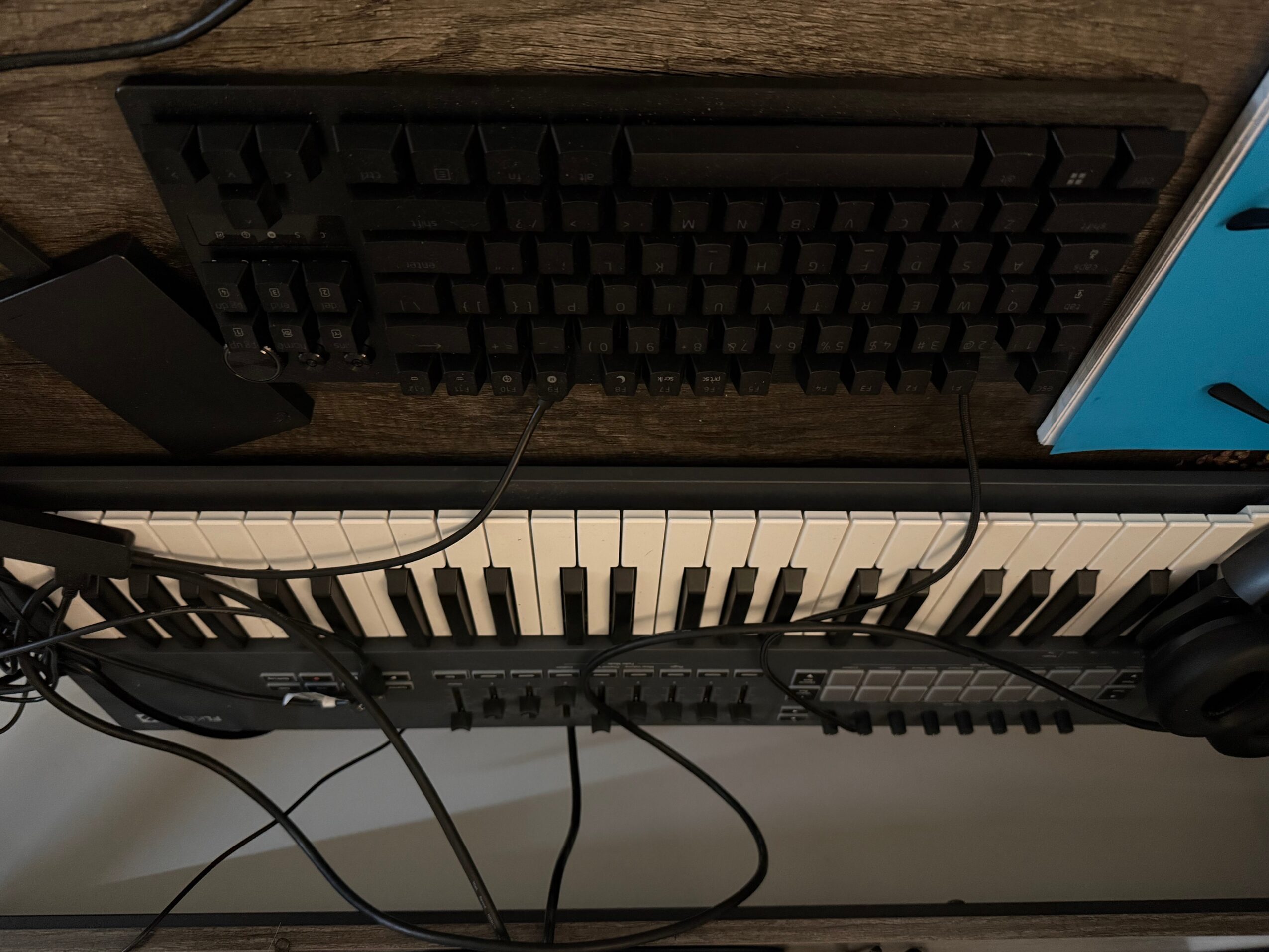 View of a keyboard, mouse, and audio equipment on a desk, with cables connected, seen from above.