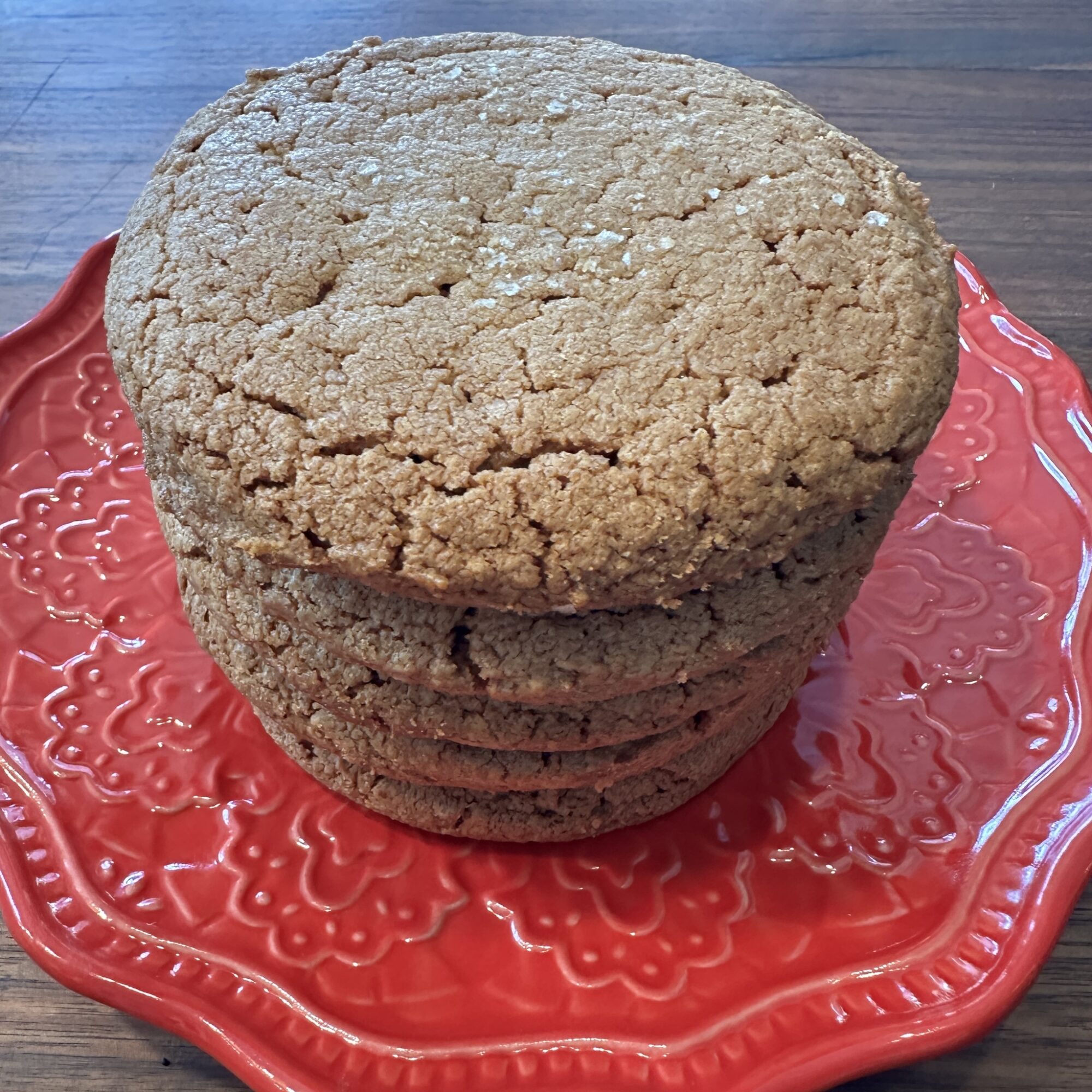 Stack of four cookies on a red decorative plate, placed on a wooden surface.