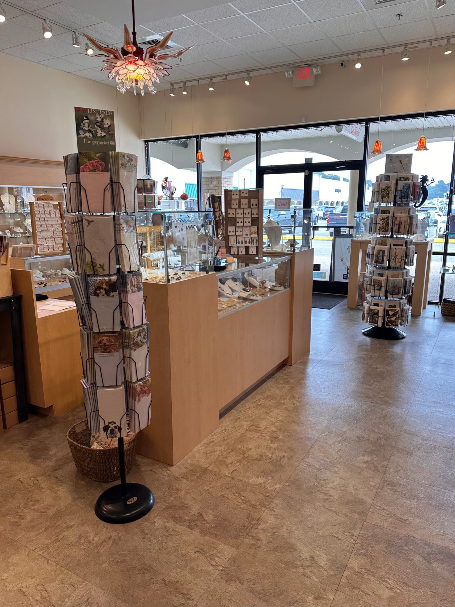 Interior of a store with display cases, a rotating jewelry stand, and large front windows showing outside view.
