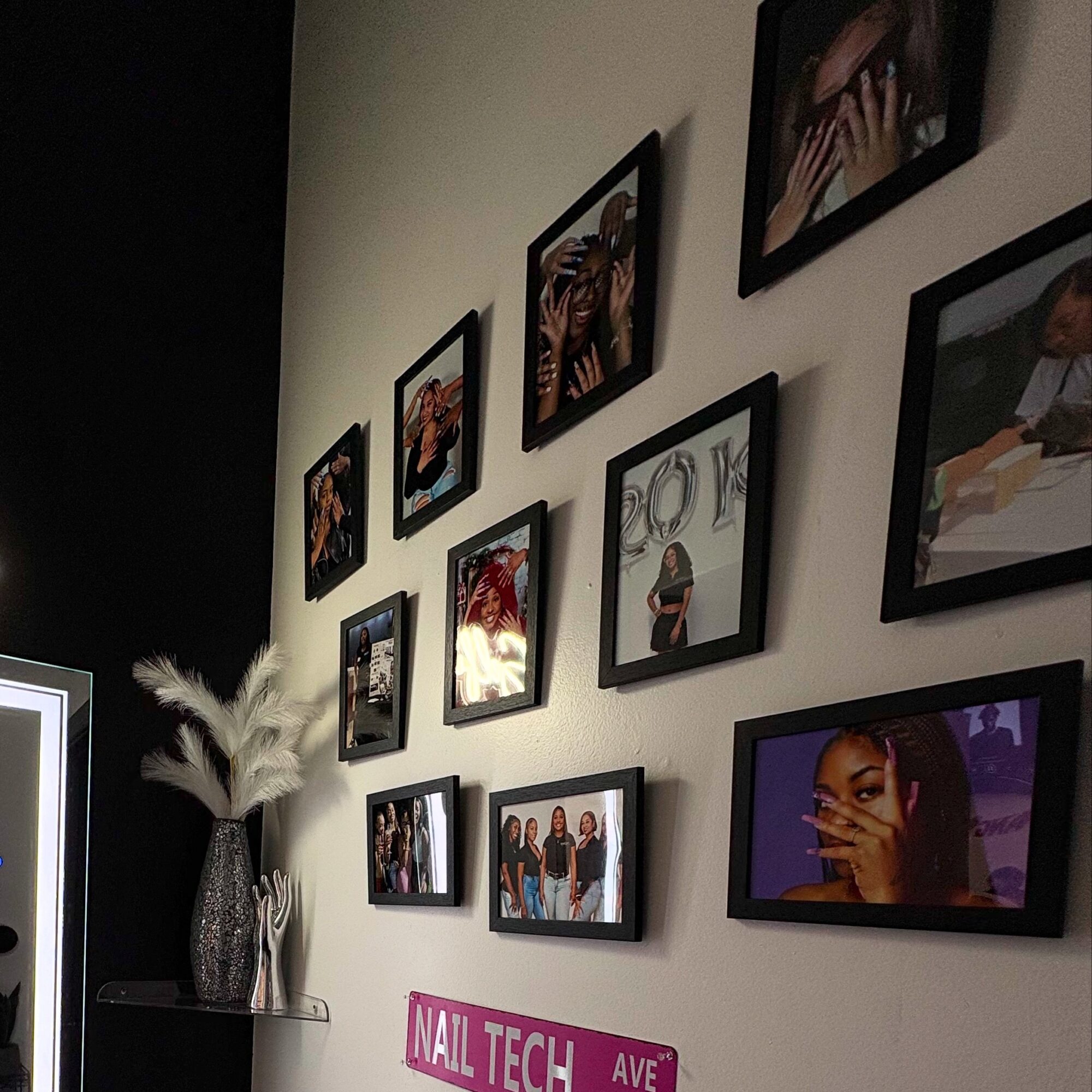 Wall with framed photos and a vase with white feathers, arranged in a gallery style.