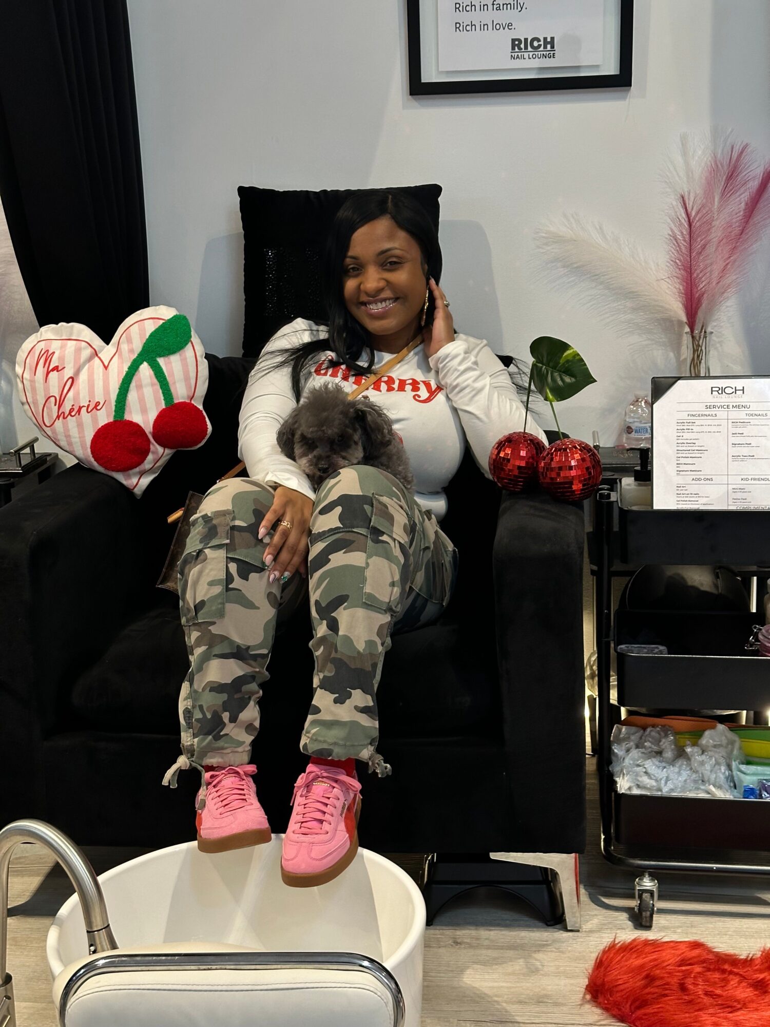 Person sitting on a black chair with a child lying across their lap, in a room with decorations and a white wall.