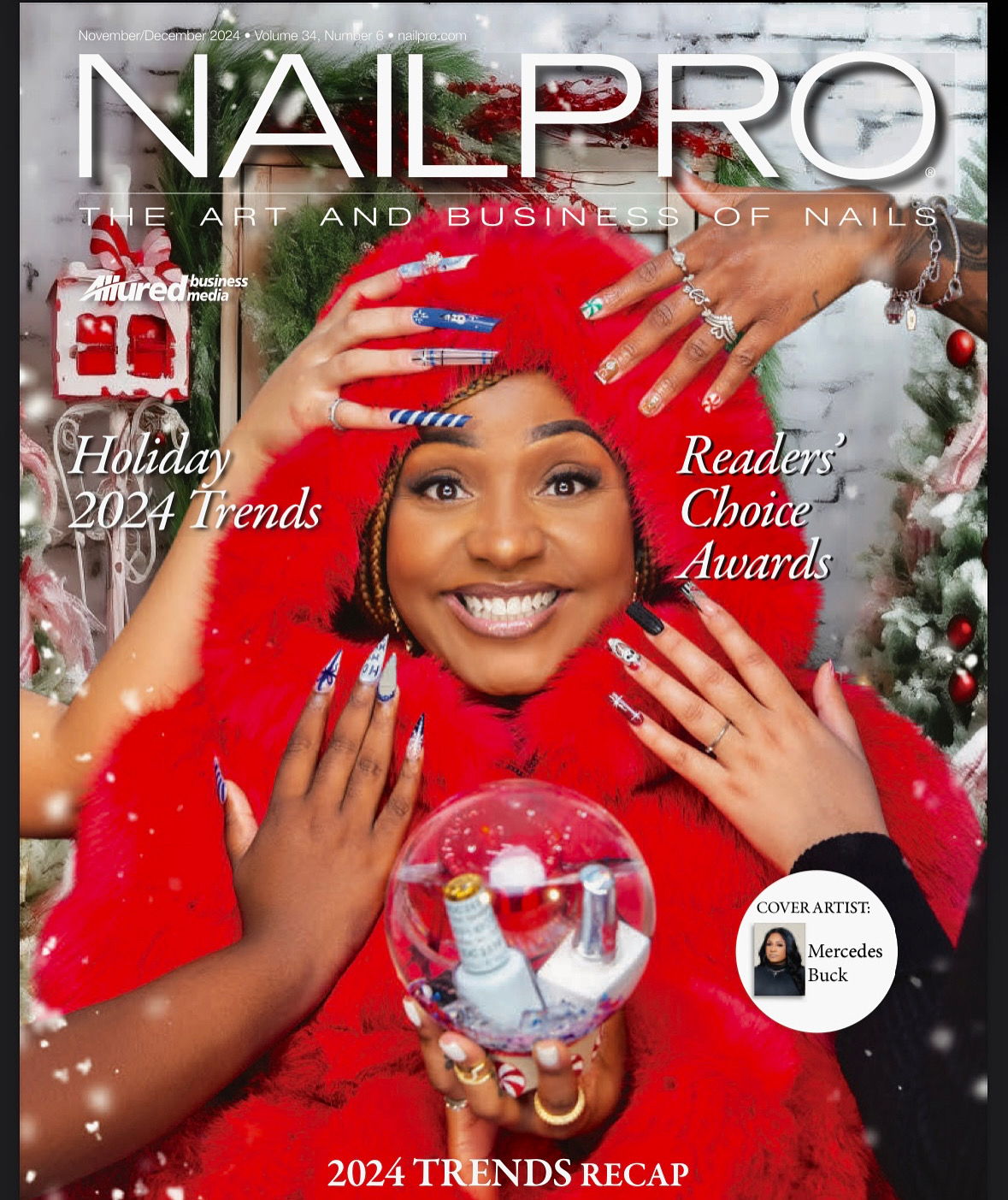 Woman with red hair and festive red sweater holding a clear ornament with nail polish bottles, smiling, holiday decorations in background.