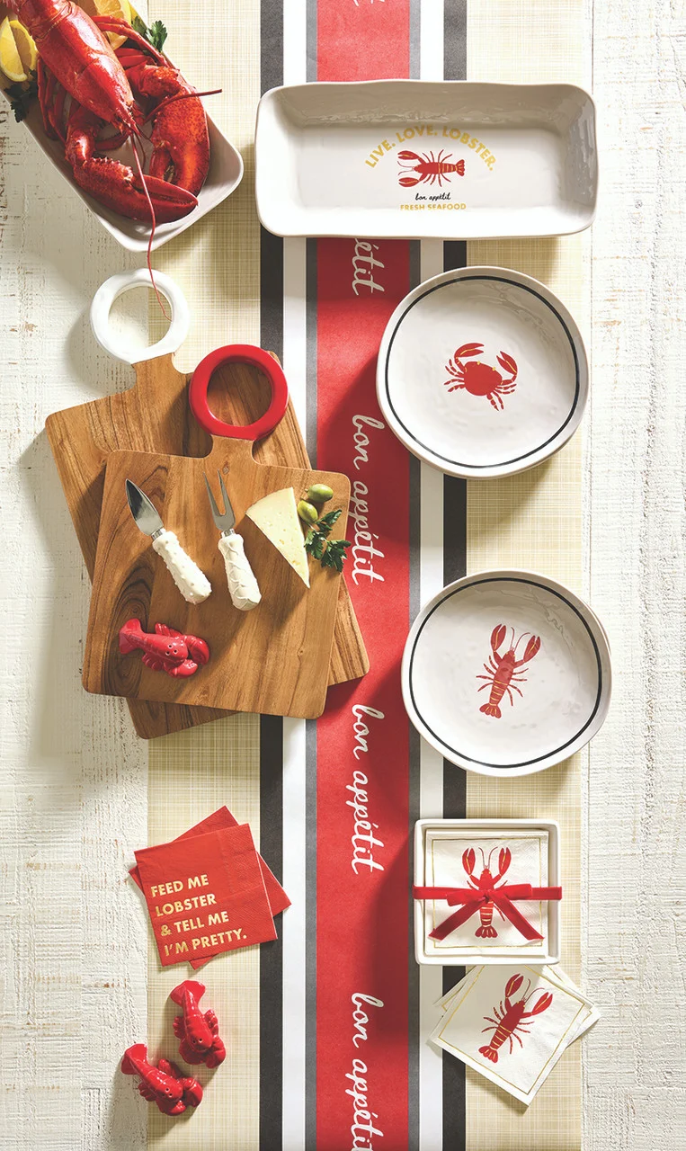 Lobster-themed table setting with plates, a wooden board, and holiday decorations on a striped surface.