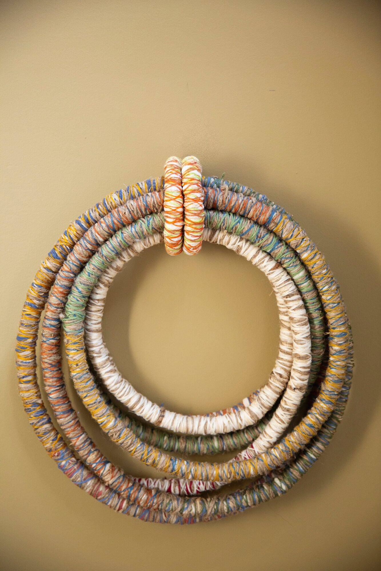 Colorful coiled jewelry or accessories arranged in a circular pattern on a plain background.