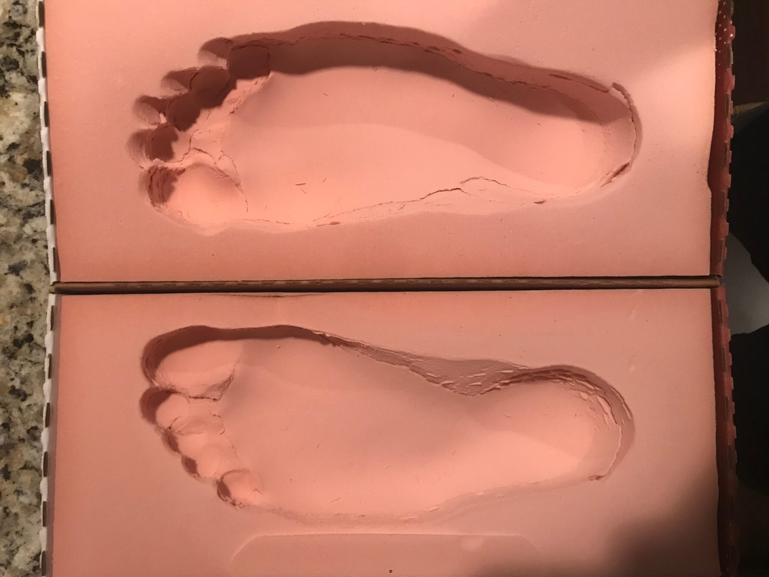 Two pink-colored footprints, one above the other, on a flat surface, with toes and heel visible.