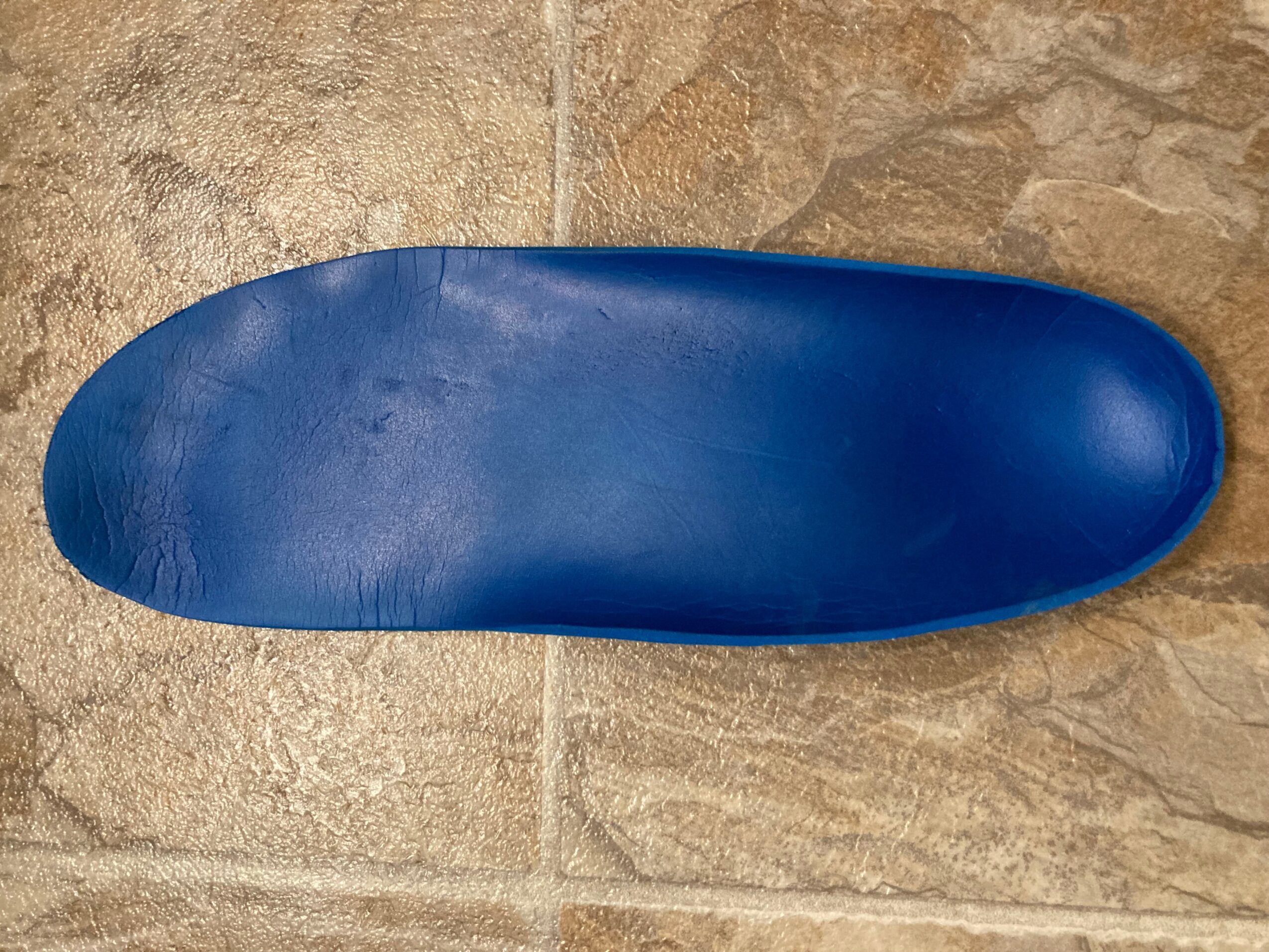 Blue shoe sole on tiled floor, viewed from above.