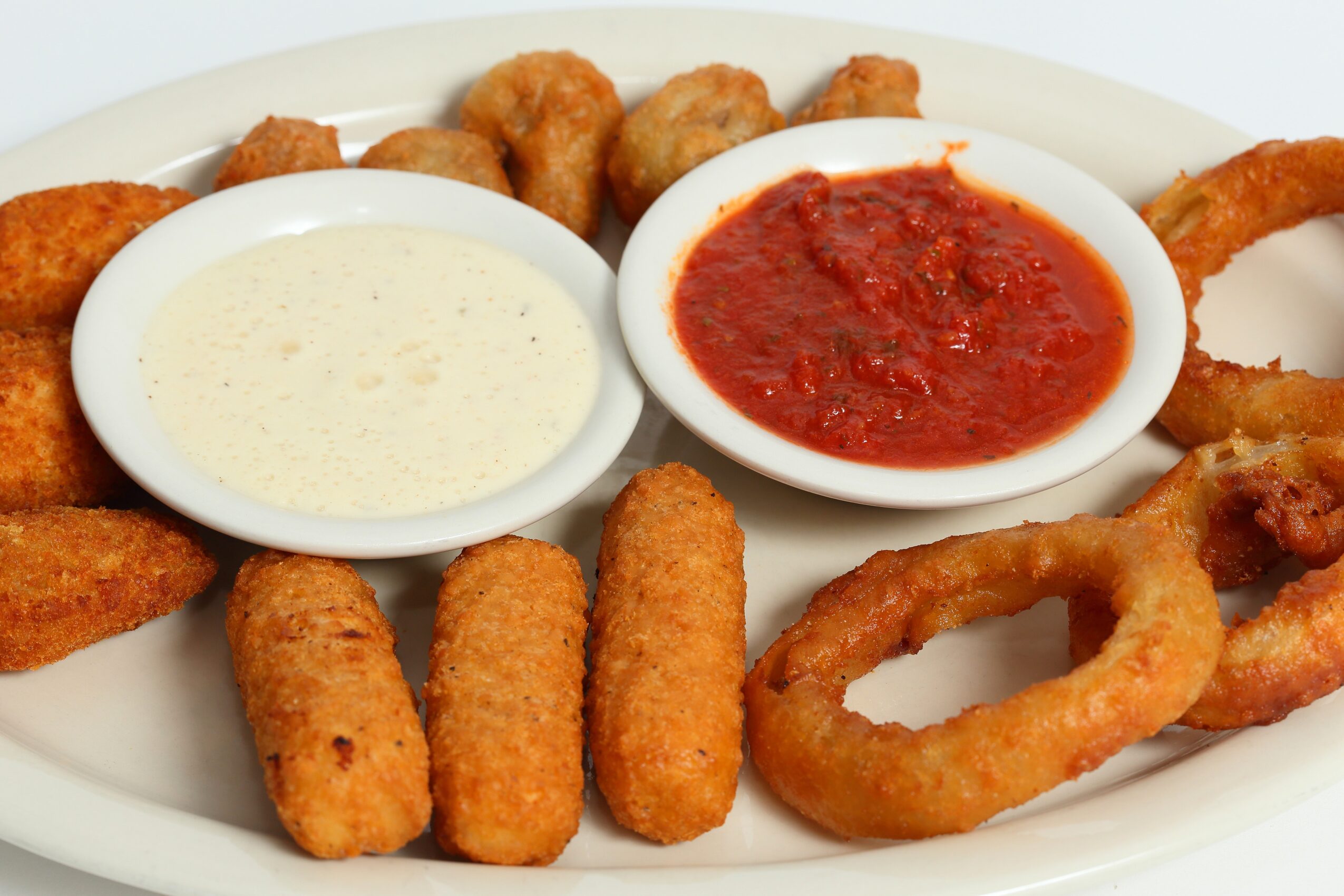Plate with fried foods, two dipping sauces, onion rings, and mozzarella sticks.