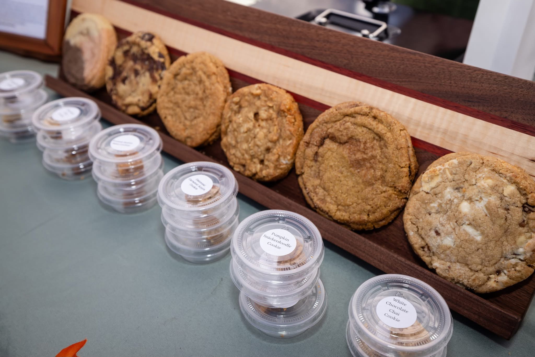 Fried food items on a wooden tray with small containers of dipping sauces, on a table surface.