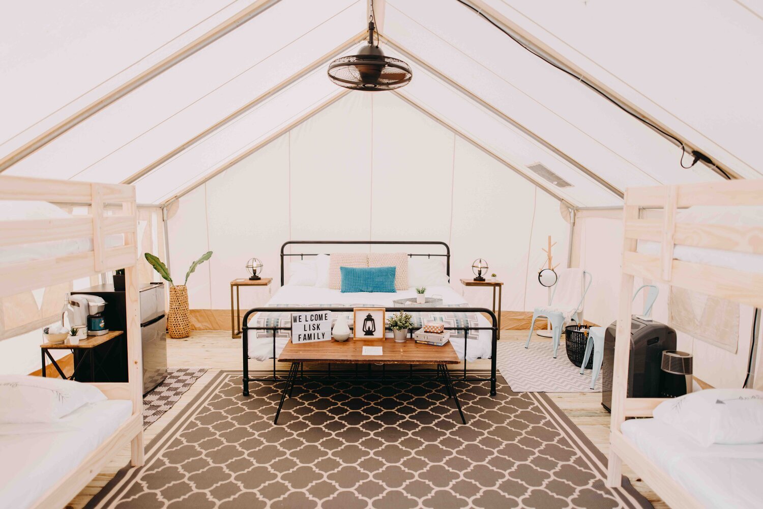 Interior of a bright, modern bedroom with a bed, two side tables, and a patterned rug, under a sloped ceiling.