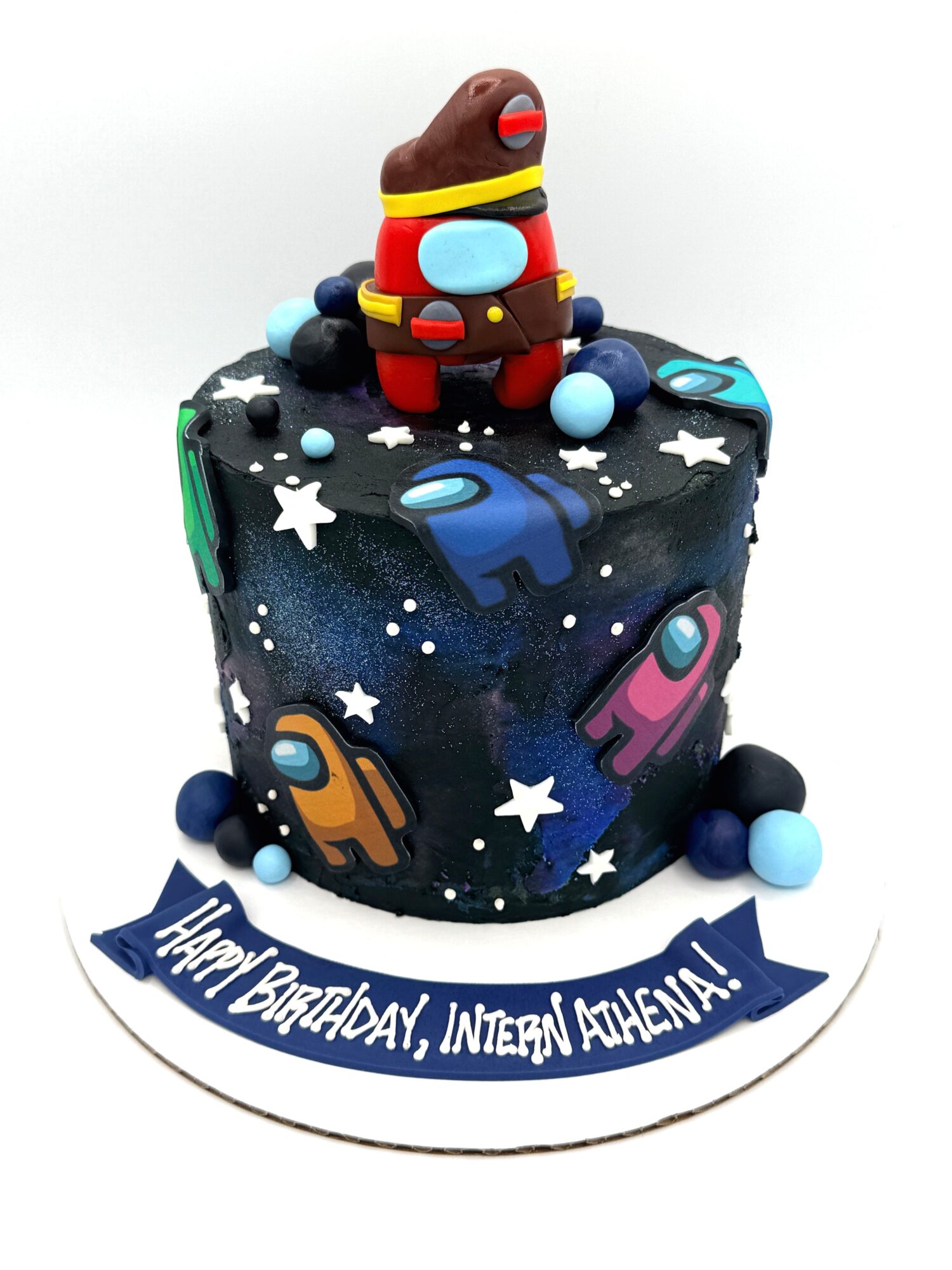 Cake decorated with space theme, featuring Among Us characters and a figure on top, with a birthday message banner.