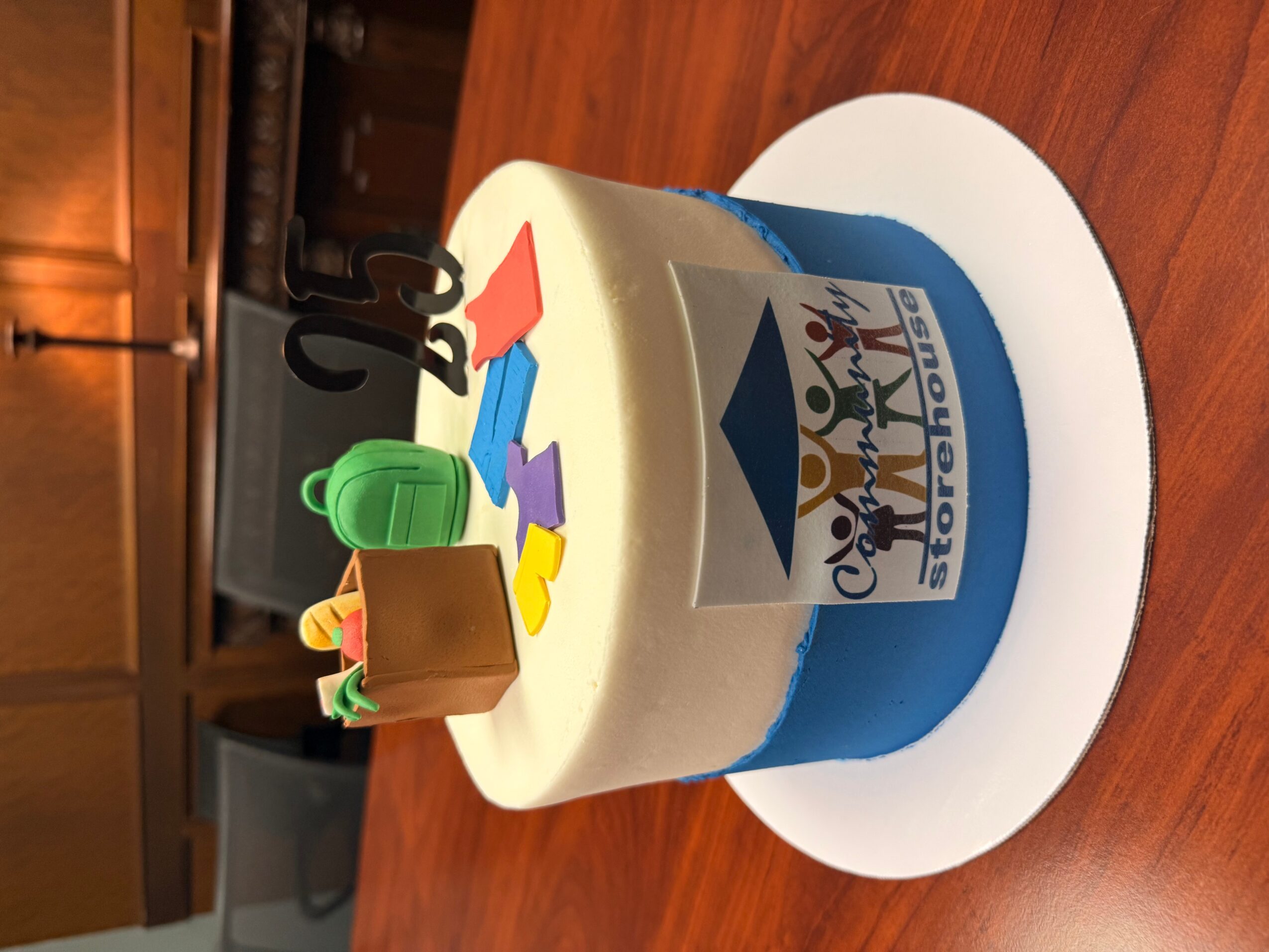 Celebration cake with a blue and white design, colorful paper decorations, and a black number '50' candle on top.