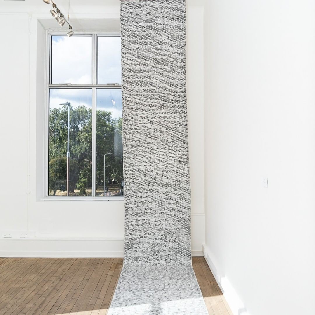 Interior room with a large window, a textured wall, and wooden floor, sunlight streaming in.