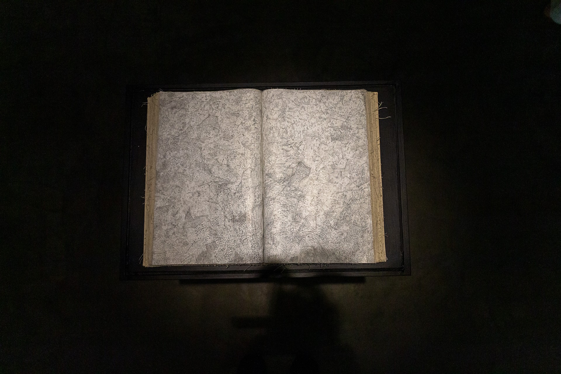Open book with blank, textured pages on a dark surface.