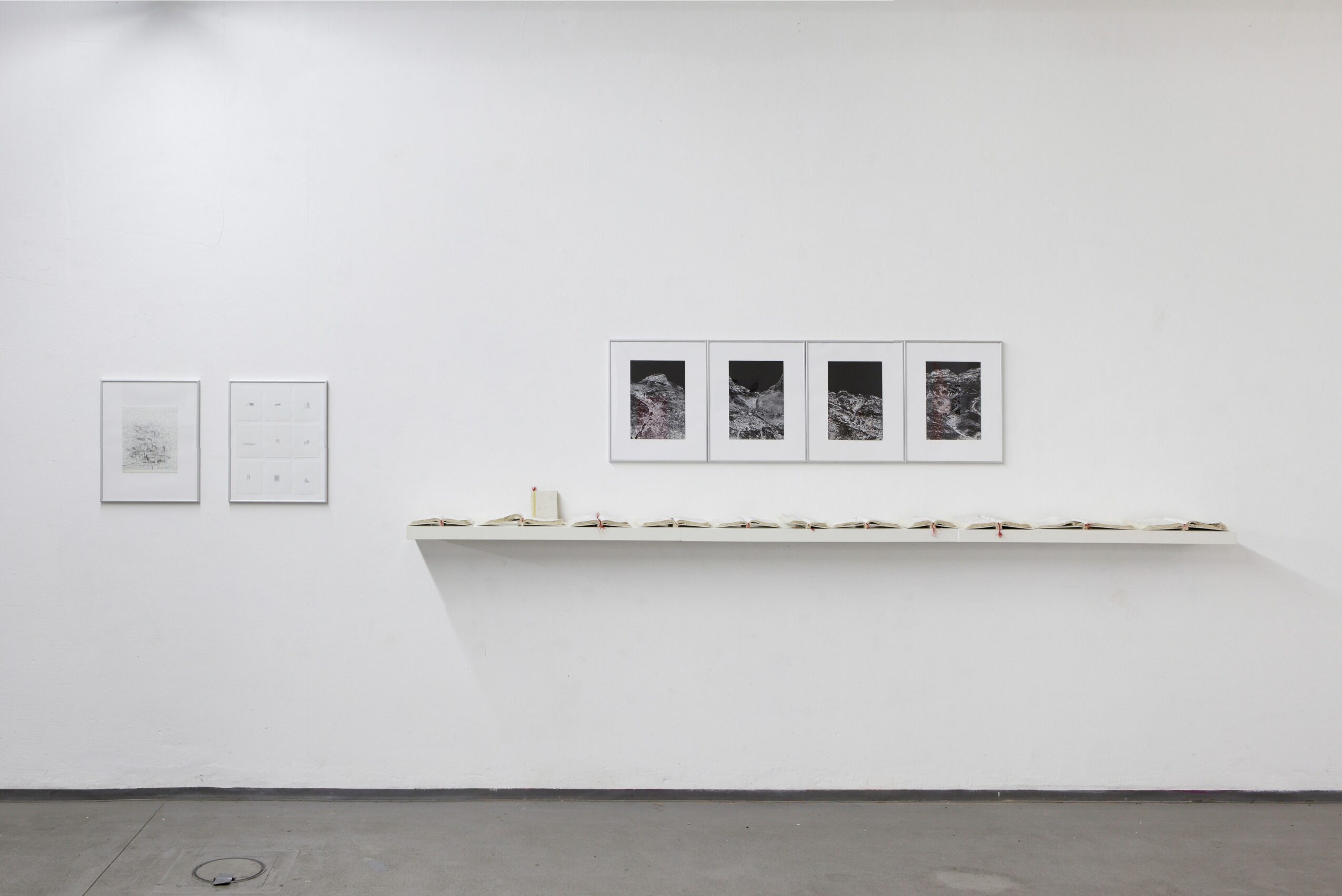 Gallery wall with framed pictures and a shelf displaying objects, against a white wall.