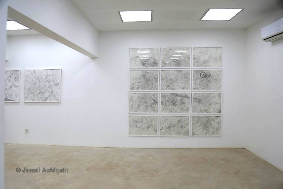 Empty white room with large window, ceiling lights, and artwork on wall, beige carpeted floor.