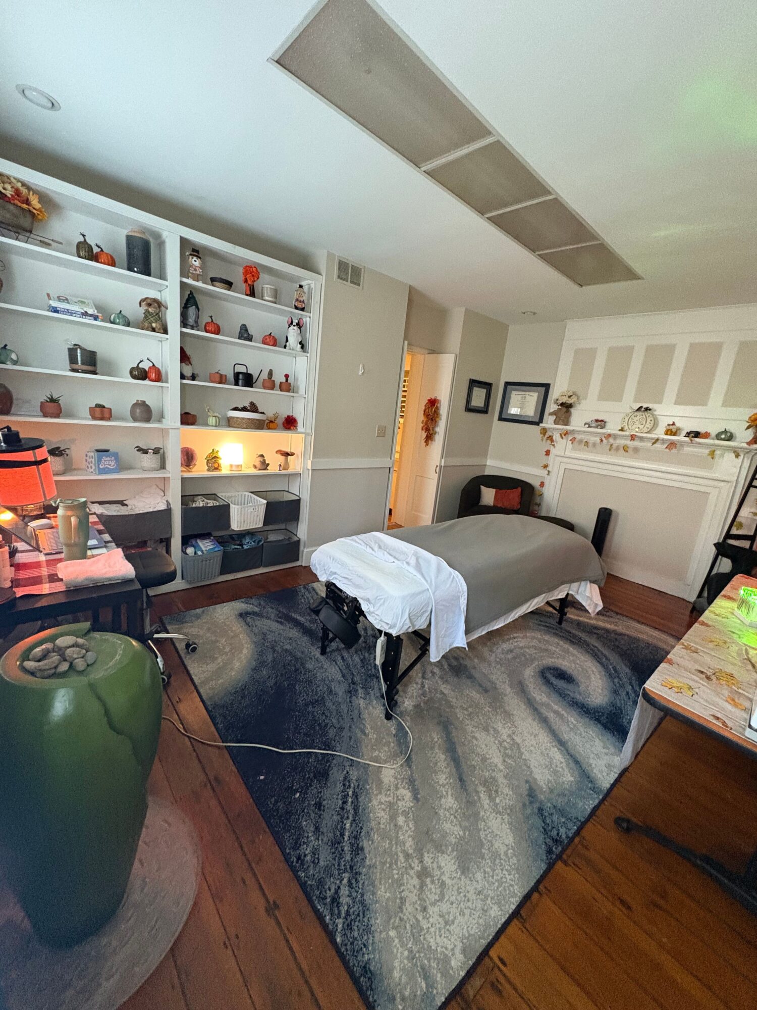 Living room with a white bookshelf, gray sofa, and a wooden floor, viewed from the side.
