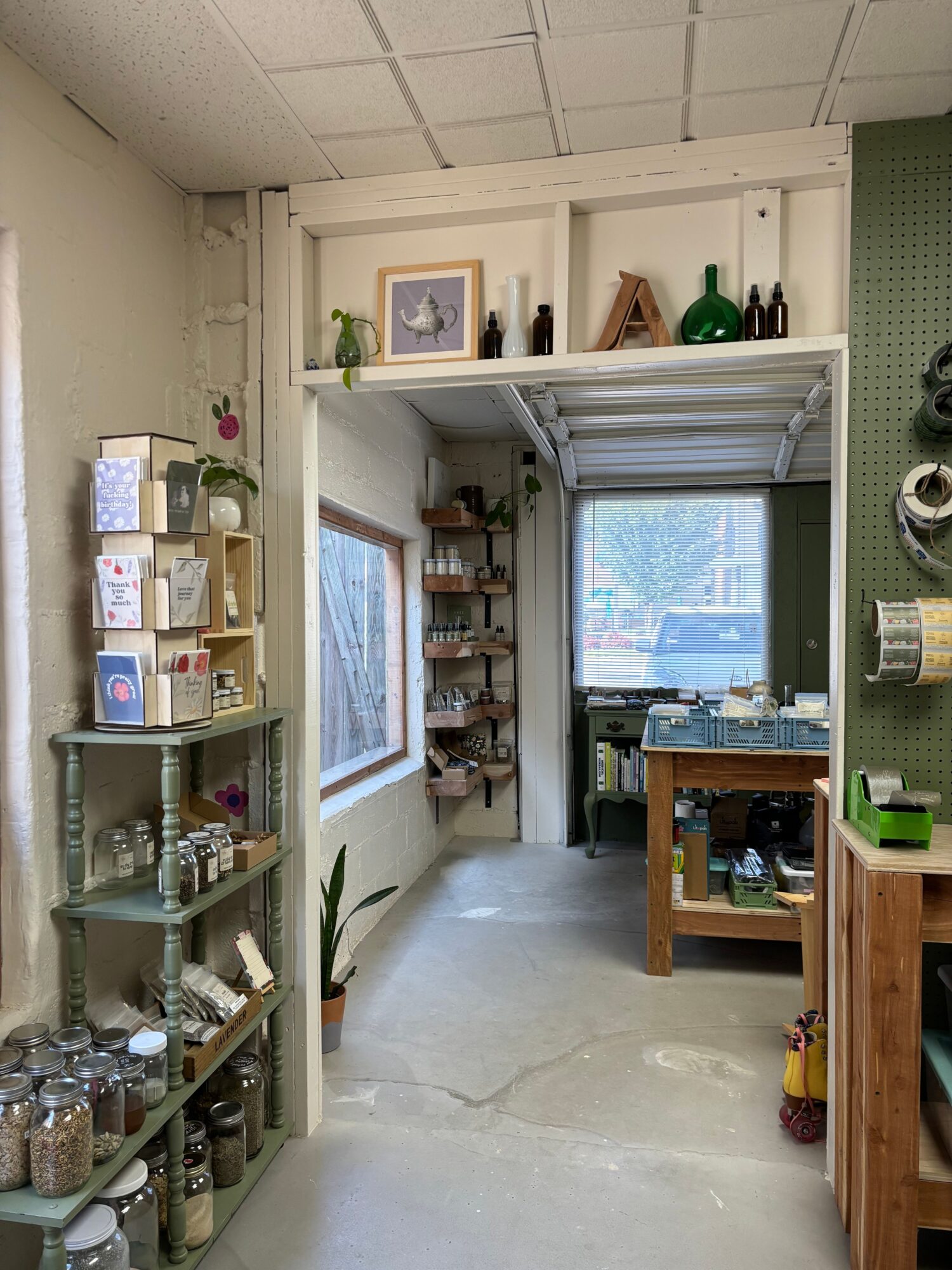 View of a workshop with shelves, a window, and various tools and supplies, seen from the side with the door open.