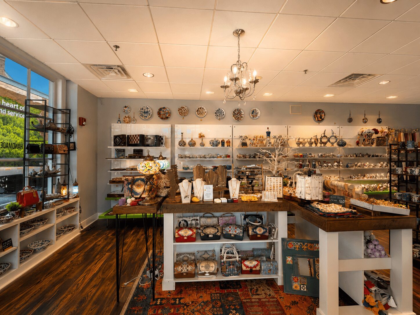 Interior of a store with shelves displaying various decorative items and accessories, wooden flooring, and a chandelier hanging from the ceiling.