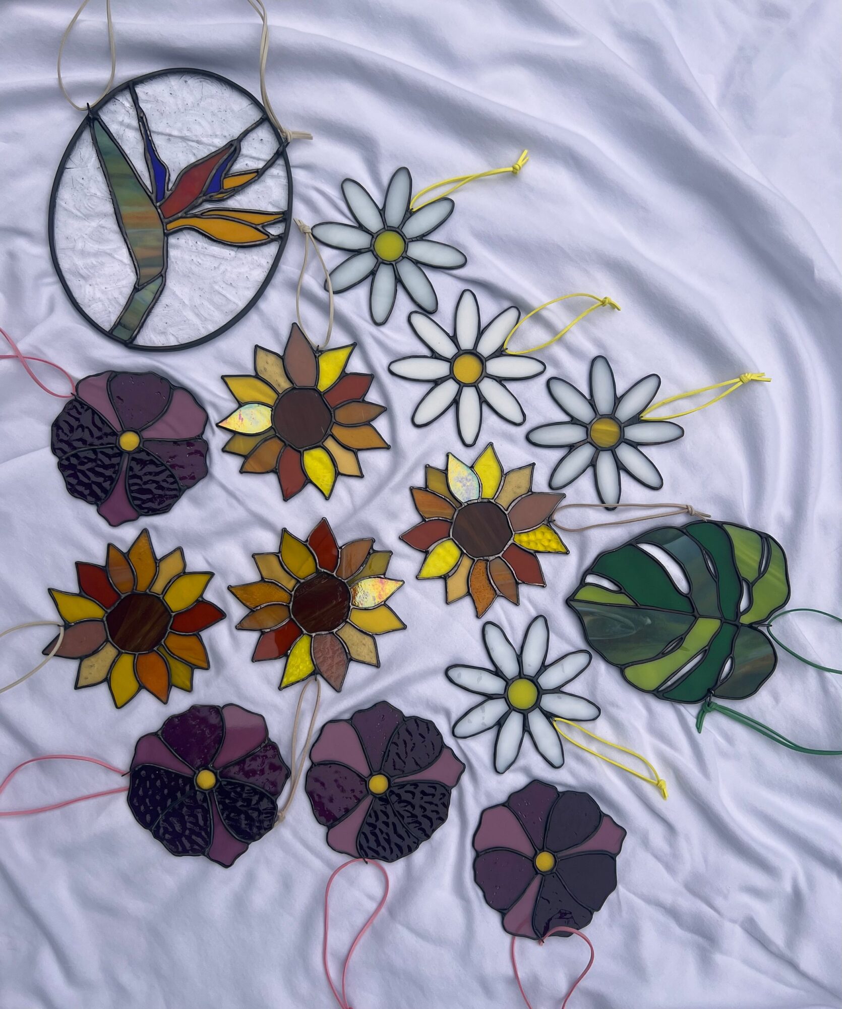 Colorful embroidered flowers and a leaf on white fabric, with some threads visible.